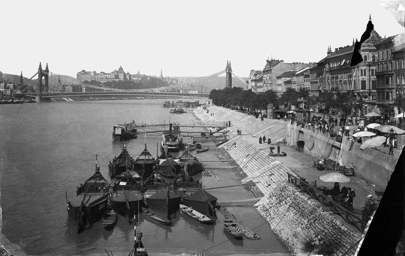 Magyarország, Budapest I., pesti alsó rakpart a Szabadság (Ferenc József) híd pesti hídfőjénél, szemben az Erzsébet híd és a budai Vár. Előtérben haltároló bárkák a Dunán., 1905, Deutsche Fotothek / Brück und Sohn, Best of, hajó, híd, napernyő, kofa, árus, lépcső, rakpart, folyópart, folyó, Budapest, Fortepan #277761