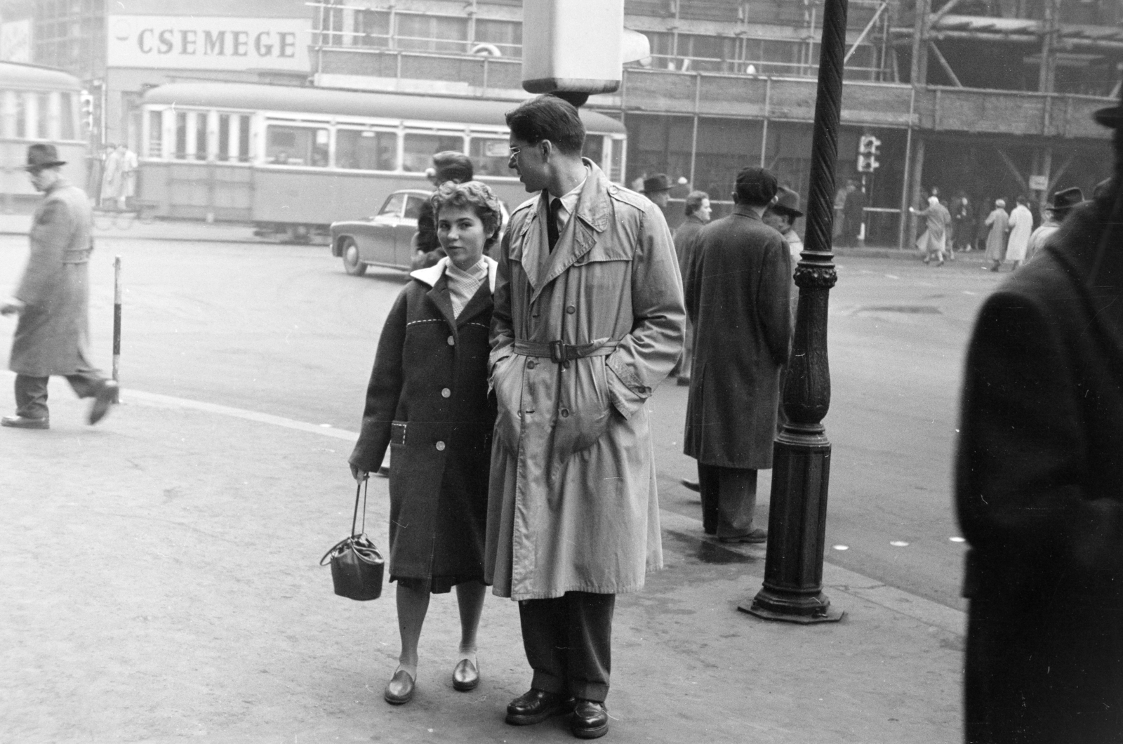 Hungary, Budapest V., a felvétel a Ferenciek terén (Felszabadulás tér) készült, háttérben a Petőfi Sándor utca sarkán álló épület látható, jobbra a Kossuth Lajos utca., 1958, Artfókusz, trench coat, man and woman, hands in pockets, youth, tram, Csemege enterprise, Budapest, Fortepan #278186