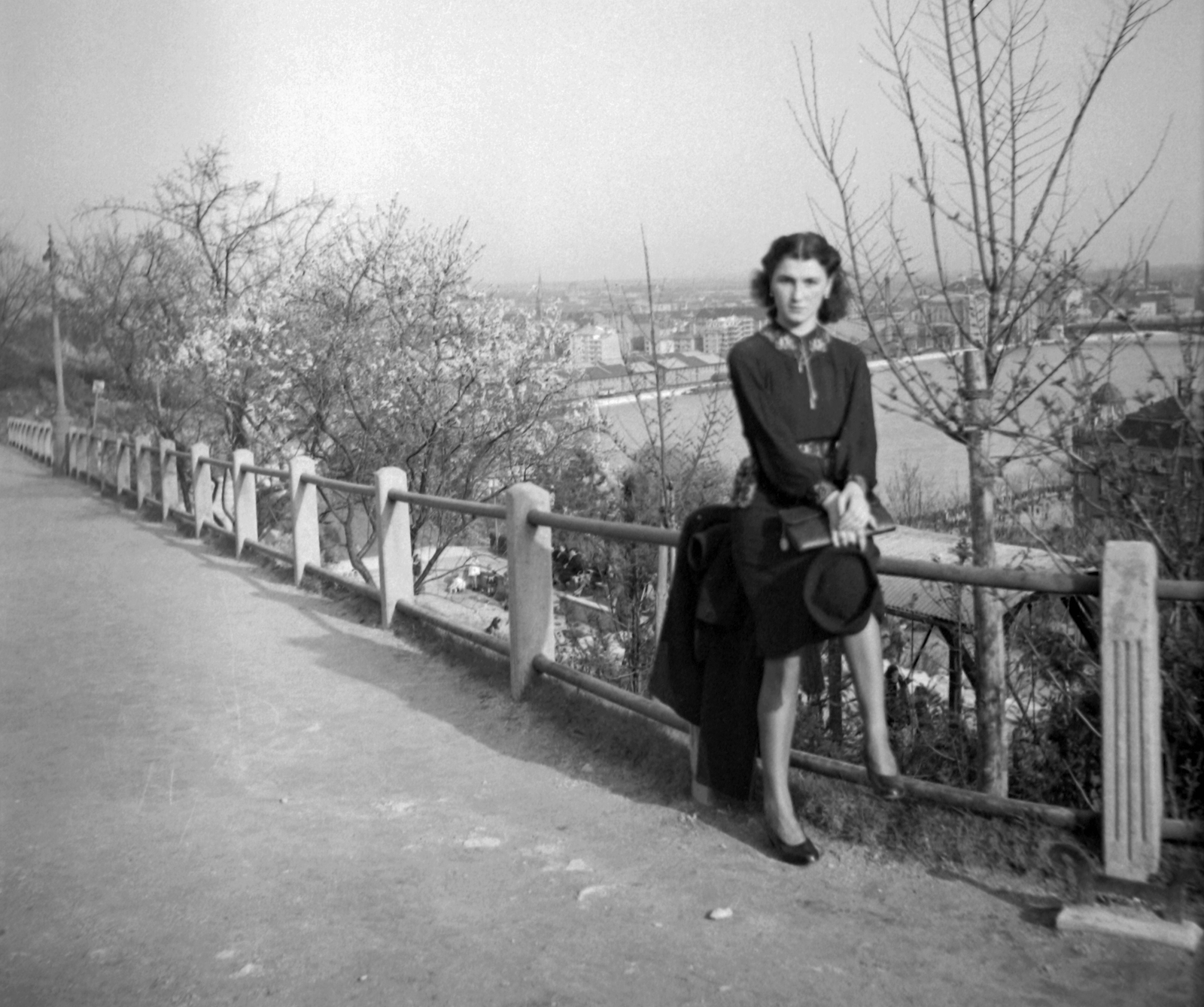 Hungary, Budapest XI., kilátás dél felé a pesti Duna-part és a Petőfi (Horthy Miklós) híd irányába., 1939, Fortepan, hat, woman, warehouse, Budapest, Duna-bridge, grain elevator, Christian Ulrich-design, Hubert Pál Álgyay-design, hat in hand, sitting on a handrail, straight face, Fortepan #28520