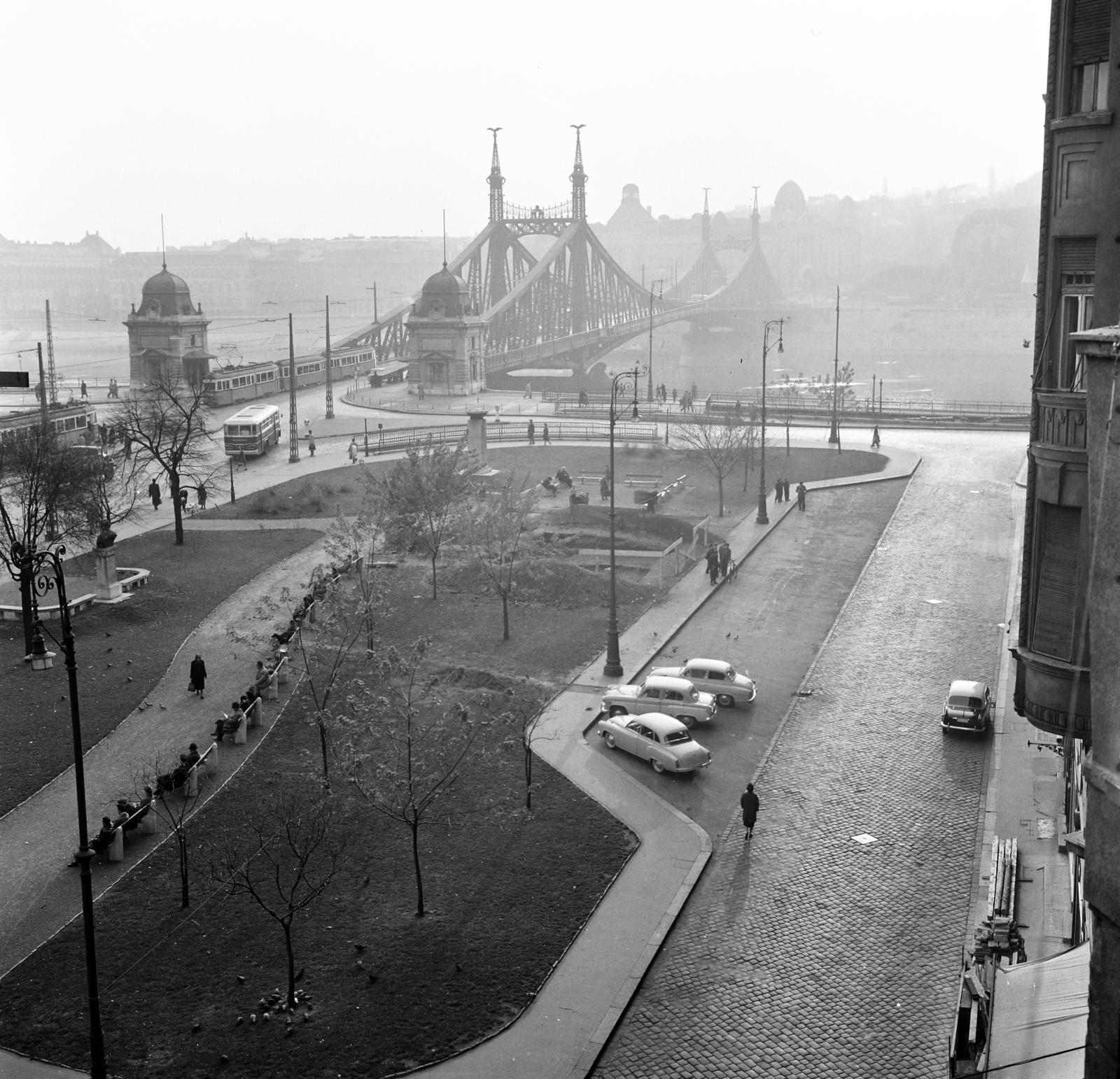 Magyarország, Budapest V.,Budapest IX.,Budapest XI., kilátás a Só utca 2-es számú ház erkélyéről a Fővám (Dimitrov) tér és a Szabadság híd felé. Balra Georgi Dimitrov mellszobra (Jordan Kracsmarov, 1954.), jobbra az I. honvéd és népfelkelő gyalogezred emlékoszlopa (Domján Árpád, 1949.). A Duna túlpartján balra a Budapesti Műszaki Egyetem (később Budapesti Műszaki és Gazdaságtudományi Egyetem) épületei., 1960, Gara család, képarány: négyzetes, tér, Budapest, Fortepan #285810