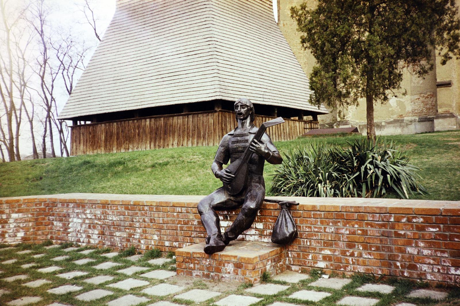 Hungary, Nyírbátor, Tinódi Lantos Sebestyén szobra (Kiss István, 1979.). Háttérben a reneszánsz fa harangtorony és a gótikus református templom., 1982, Kozák, colorful, Fortepan #286692