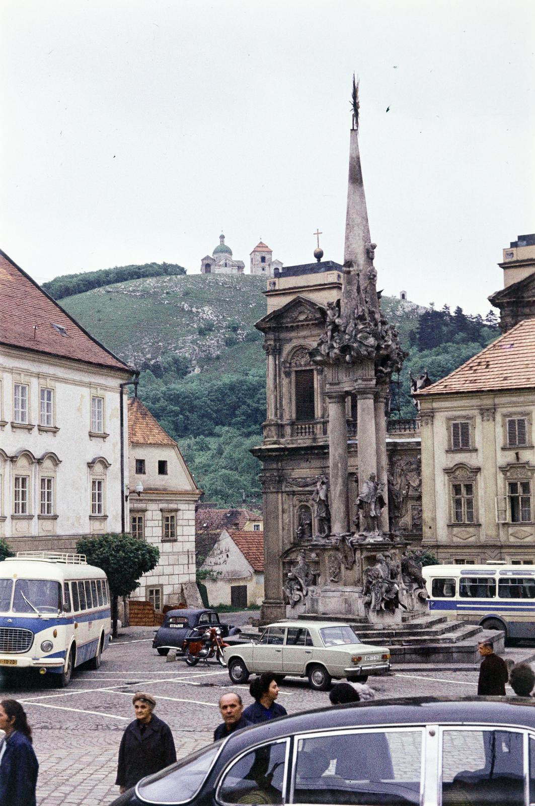Csehország, Mikulov, a történelmi főtér (Náměstí), a Szentháromság szobor mögött a Ditrichštejn család síremléke (Dietrichsteinská hrobka) a Szent Anna-templommal. Háttérben a Szent Domb (Svatý kopeček), tetején a XVII. századi barokk Szent Sebestyén-templom., 1974, Csaba László örökösei, Fortepan #288302
