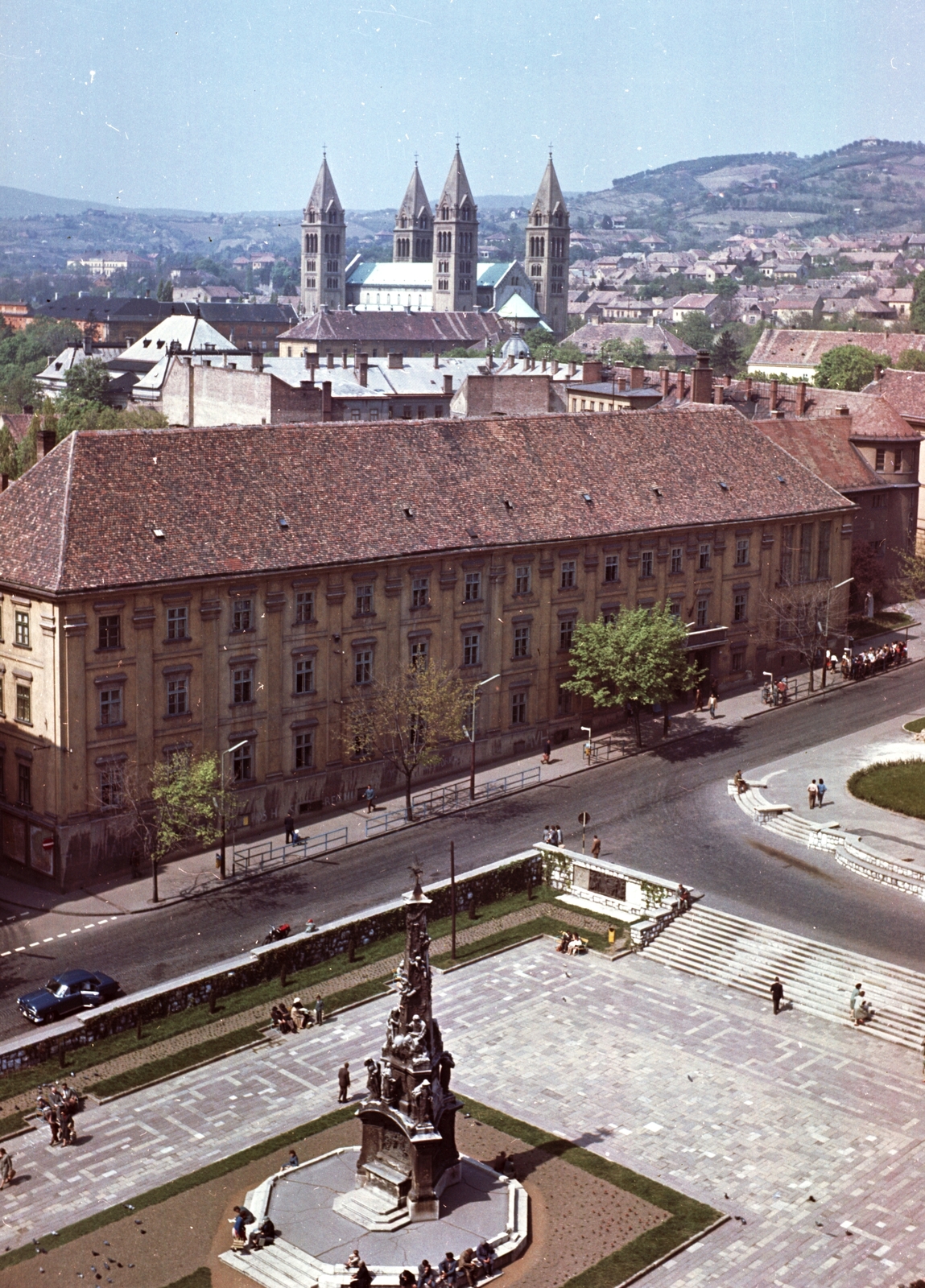 Magyarország, Pécs, Széchenyi tér, Szentháromság-szobor valamint a Ciszterci Rend Nagy Lajos Gimnáziuma és Kollégiuma. Látkép a Városháza tornyából a Székesegyház felé nézve., 1965, Építésügyi Dokumentációs és Információs Központ, VÁTI, színes, emlékmű, utcakép, városkép, Bazilika, katolikus, neoromán építészet, székesegyház, Fortepan #29077