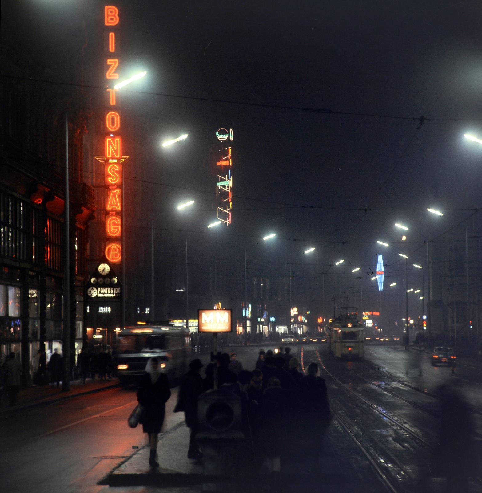 Magyarország, Budapest V., villamosmegálló a Szabad sajtó útnál, szemben a kivilágított Ferenciek tere (Felszabadulás tér) és a Kossuth Lajos utca., 1971, Inkey Tibor, éjszaka, színes, neon felirat, Budapest, Fortepan #292740
