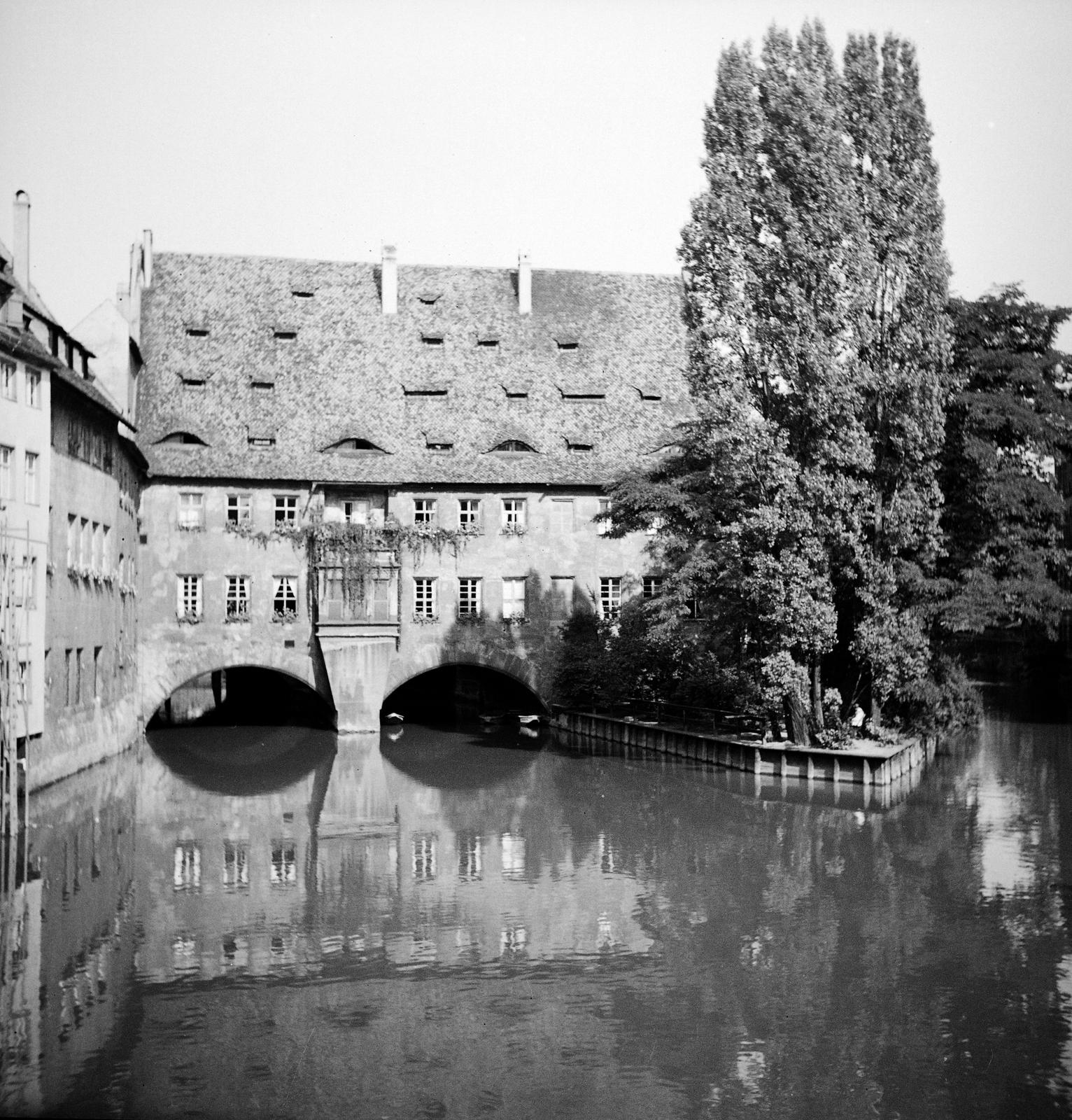 Németország, Nürnberg, a Pegnitz folyó a Múzeum-hídról a Schütt szigeten álló Heilig-Geist-Spital felé nézve., 1936, Kenderessy Tibor, boltív, jegenyefa, víztükör, Fortepan #292969