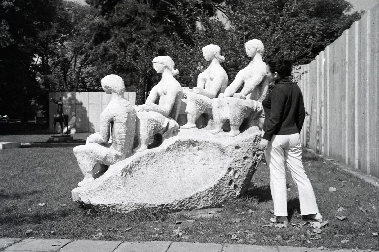 Magyarország, Budapest XIV., Olof Palme sétány (Népstadion út), park az 1885-ös Országos Általános Kiállításra épült Műcsarnok előtt. 1954-től szobrászok, kőfaragók műhelye. Később a Képzőművészeti Kivitelező Vállalat székhelye. Olvasó lányok (Kerényi Jenő, 1963.). A szobor 1965. óta Oroszlányban áll., 1975, Fortepan/Album100, Budapest, Fortepan #293814