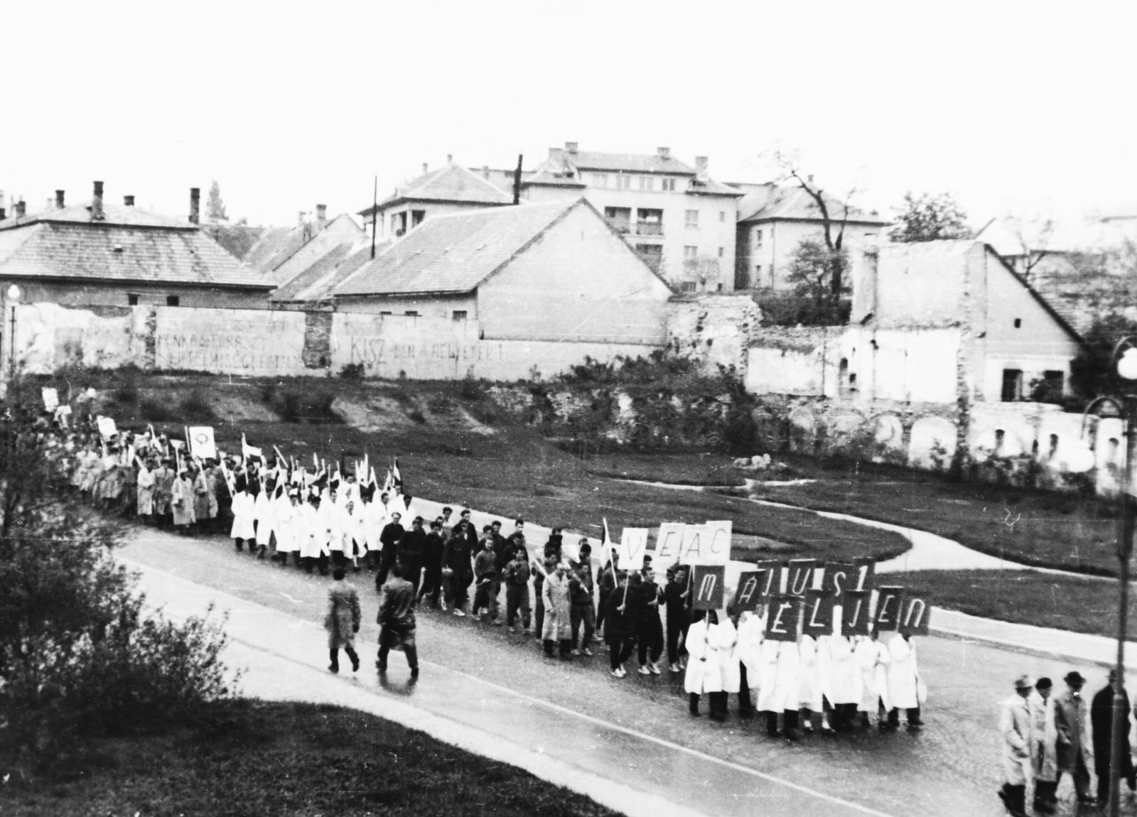 Magyarország, Veszprém, Egyetem (Schönherz Zoltán) utca, a Veszprémi Vegyipari Egyetem dolgozói és hallgatói a május 1-i felvonuláson. Az üres területre épült később, a kórház rendelőintézete., 1957, Polinszky Tibor, Fortepan #295681