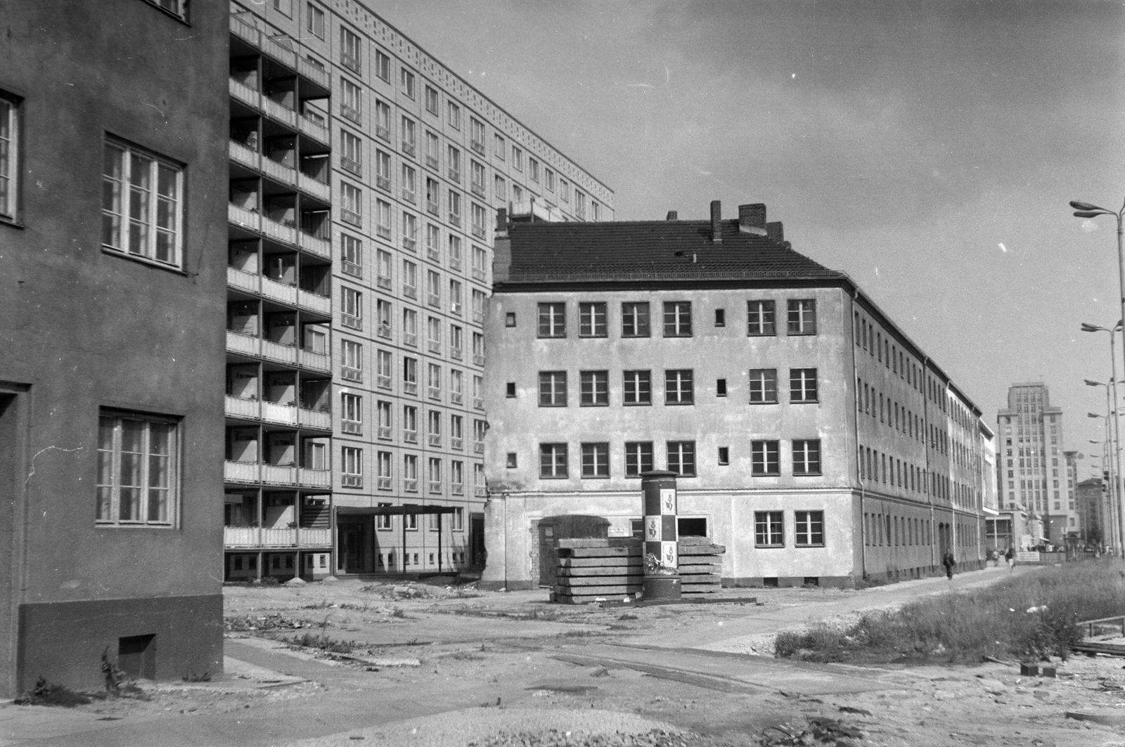 Németország, Berlin, Kelet-Berlin, Karl-Marx-Allee. A bontásra váró régi ház mögött fehérlik a Kino International épülete, a távolban látszik a Strausberger platz sarkán álló toronyépület., 1964, Szomolányi József, hirdetőoszlop, magasház, Fortepan #302614