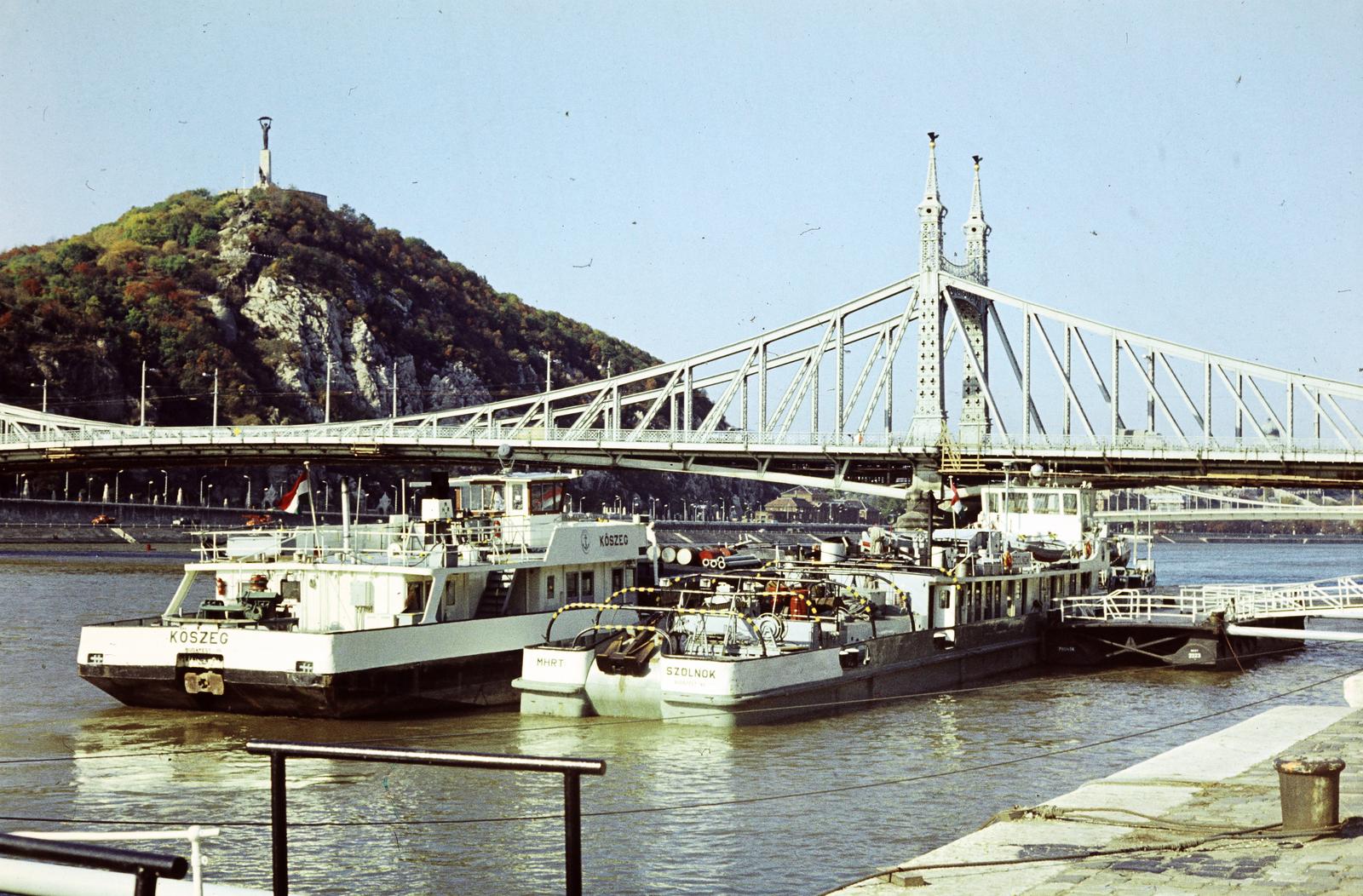 Magyarország, Budapest IX.,Budapest XI., a pesti alsó rakpart Fővám (Dimitrov) térnél, szemben a Szabadság híd, balra háttérben a Gellért-hegy., 1975, Szomolányi József, színes, hajó, Budapest, Fortepan #302659