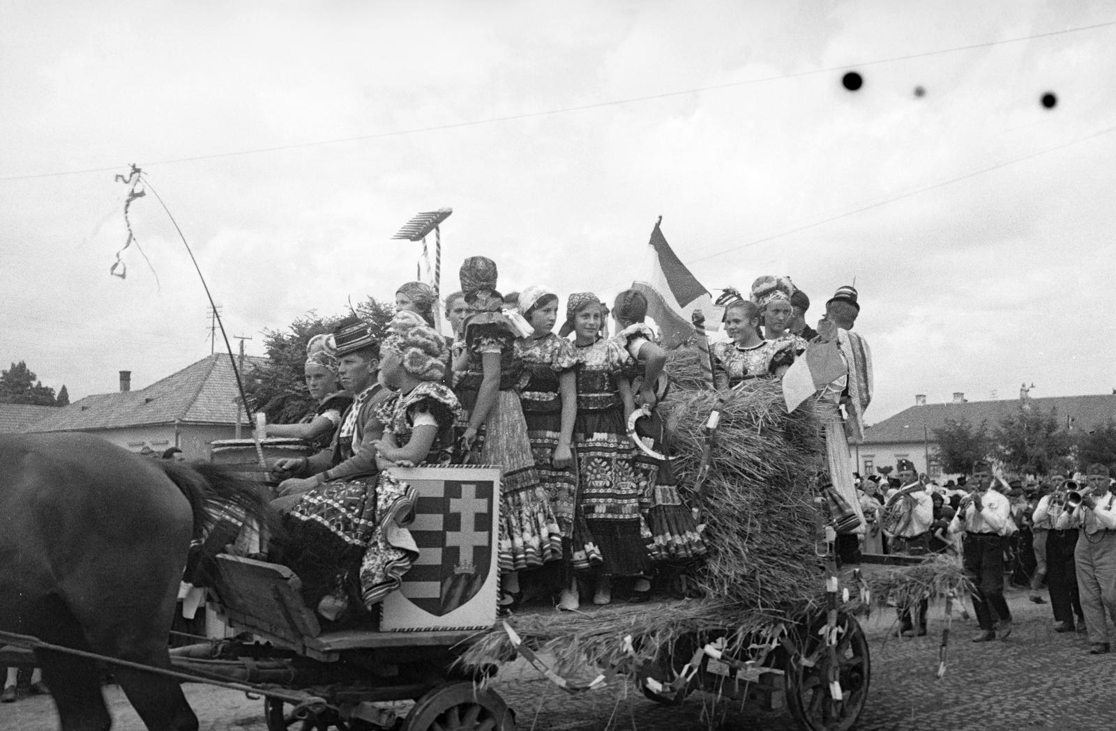 Hungary, Mezőkövesd, Mátyás király út, matyó népviseletben felvonuló fiatalok., 1938, Inkey Tibor, Best of, Horse-drawn carriage, folk costume, march, wind band, Kossuth coat of arms, Fortepan #304755