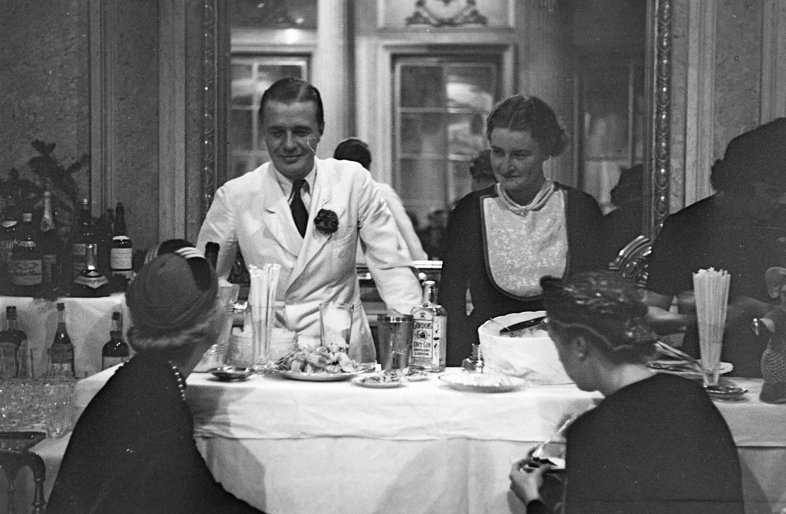 Hungary, Budapest VIII., Reviczky utca 6., Károlyi-Csekonics palota. Az ezévi jótékony célú bazár rendezvény bárjában a mixer gróf Szapáry Antal és gróf Szapáry Erzsébet.
, 1937, Inkey Tibor, table, hospitality, flower on a lapel, drink, Budapest, Fortepan #305164