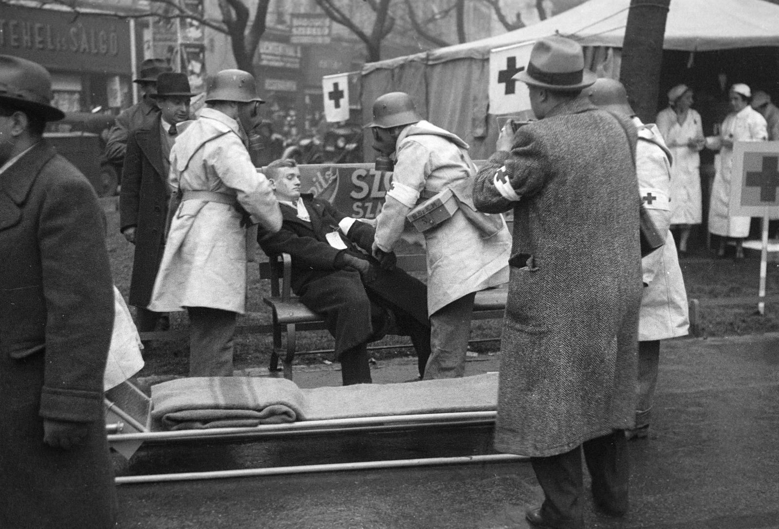 Hungary, Budapest V., Deák Ferenc tér. A felvétel a védelmi alakulatok légoltalmi gyakorlatán készült. A vöröskeresztes mentőcsapat tagjai elszállítják a sebesültet., 1937, Inkey Tibor, Best of, wounded, practice, tent, photography, armband, air defense, gas mask, barrow, Budapest, Fortepan #305175