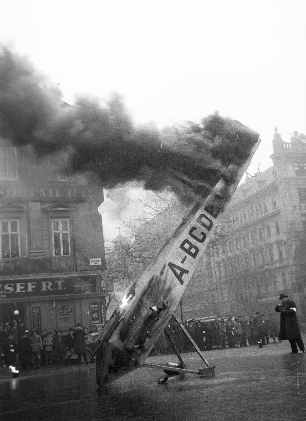 Magyarország, Budapest V., Deák Ferenc tér, balra a háttérben a Kemnitzer ("Két török") ház, jobbra Bajcsy-Zsilinszky út (Vilmos császár út) - Anker köz sarkán álló ház látható. A felvétel a védelmi alakulatok légoltalmi gyakorlatán készült., 1937, Inkey Tibor, utcanévtábla, gyakorlás, járműroncs, füst, repülőgép, Budapest, Fortepan #305191