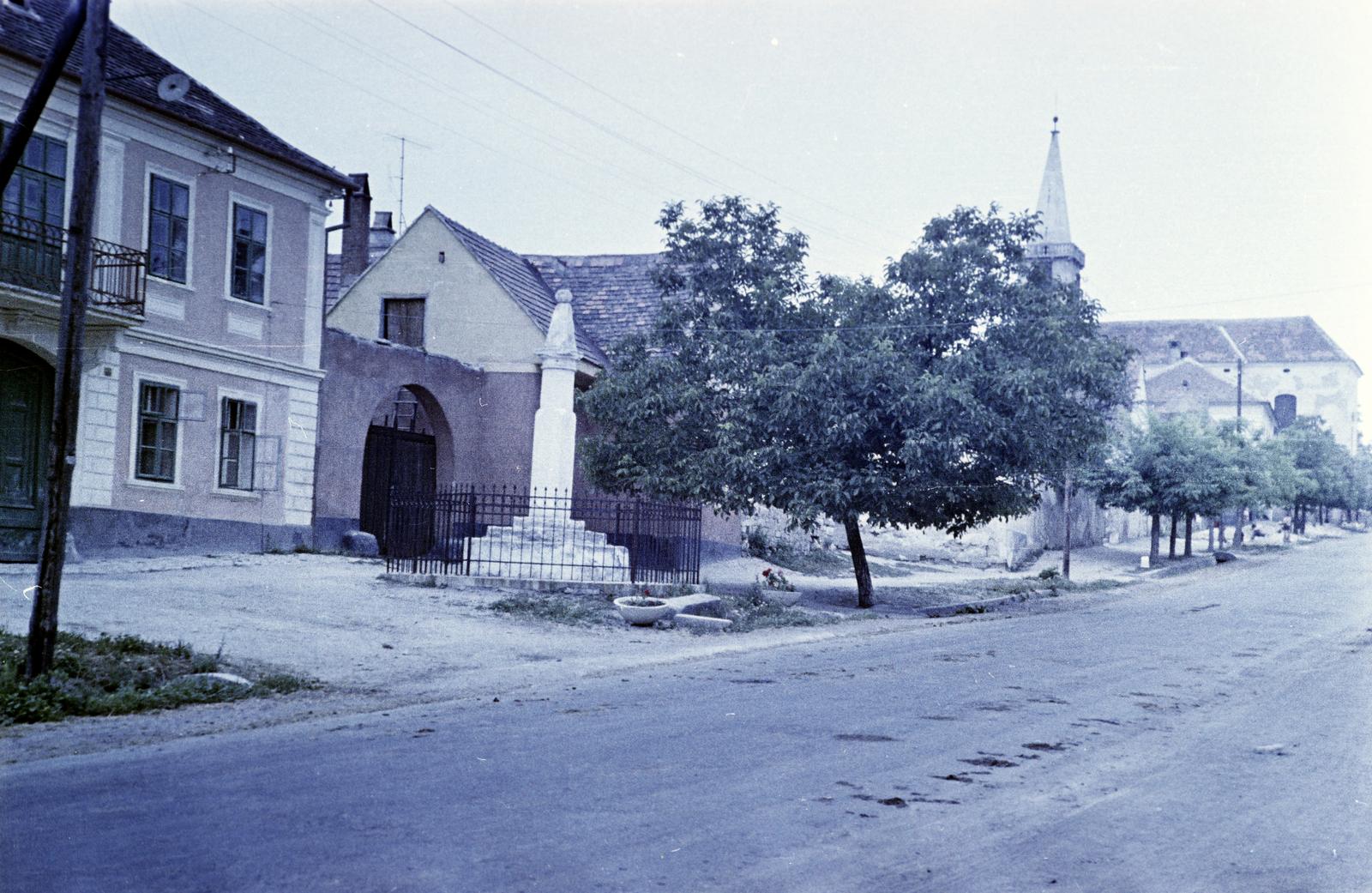 Magyarország, Fertőrákos, Fő utca, pellengér (szégyenoszlop), háttérben balra a Községháza, jobbra fent az Urunk Mennybemenetele-templom., 1960, Gazda Anikó, emlékmű, színes, földút, Fortepan #307044