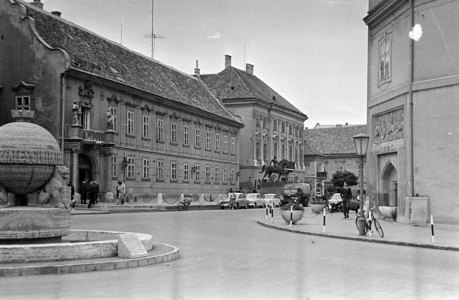 Hungary, Székesfehérvár, Városház (Szabadság) tér, balra az Országalma (Ohmann Béla, 1943.). Szemben a Városháza előtt a Tízes huszárok szobra (Pátzay Pál, 1939.). Jobbra a Szent Imre-templom oldalfalán Medgyessy Ferenc szobrászművész alkotása, a Török–magyar csata, emlékkút (1938)., 1965, Gazda Anikó, Fortepan #307223