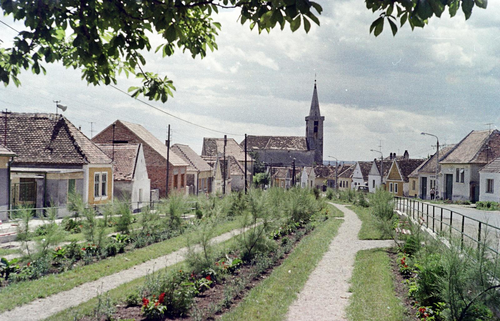 Magyarország, Fertőrákos, Fő utca, háttérben az Urunk Mennybemenetele templom., 1968, Gazda Anikó, Best of, színes, lakóház, oromfal, templom, hangszóró, virágágyás, templomtorony, Fortepan #307346