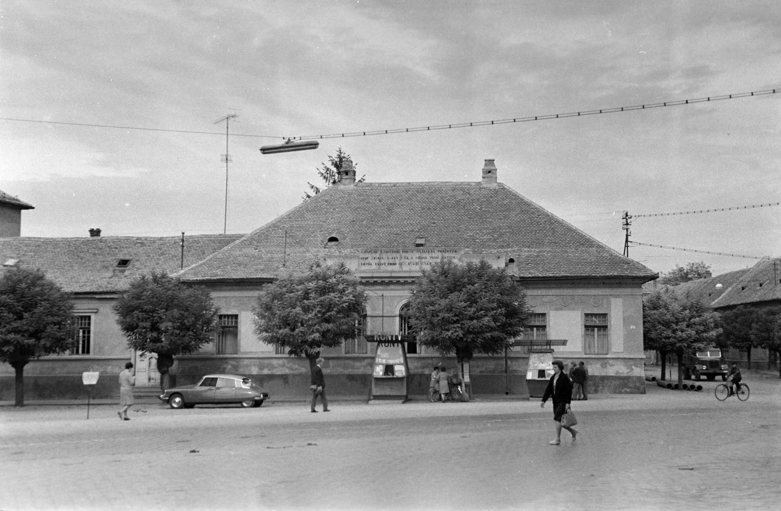 Magyarország, Baja, Tóth Kálmán tér, szemben a katolikus parókia épülete, attól jobbra a Táncsics Mihály utca torkolata., 1962, Gazda Anikó, pavilon, könyvárus, Fortepan #307423
