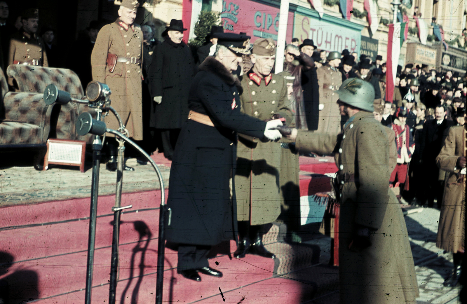 Hungary, Nyíregyháza, Kossuth tér, ünnepség a frontról hazatért katonák tiszteletére a Városháza előtt 1941. november 17-én. Horthy Miklós kormányzó az ünnepség keretében kitüntetést ad át. Mellette Keresztes-Fischer Lajos altábornagy, hátul Bartha Károly vezérezredes, honvédelmi miniszter., 1941, Fortepan, celebrity, colorful, uniform, flag, military, festive, microphone, store display, handshake, shoe store, Frigyes Stühmer chocolate factory, officer, Fortepan #3076