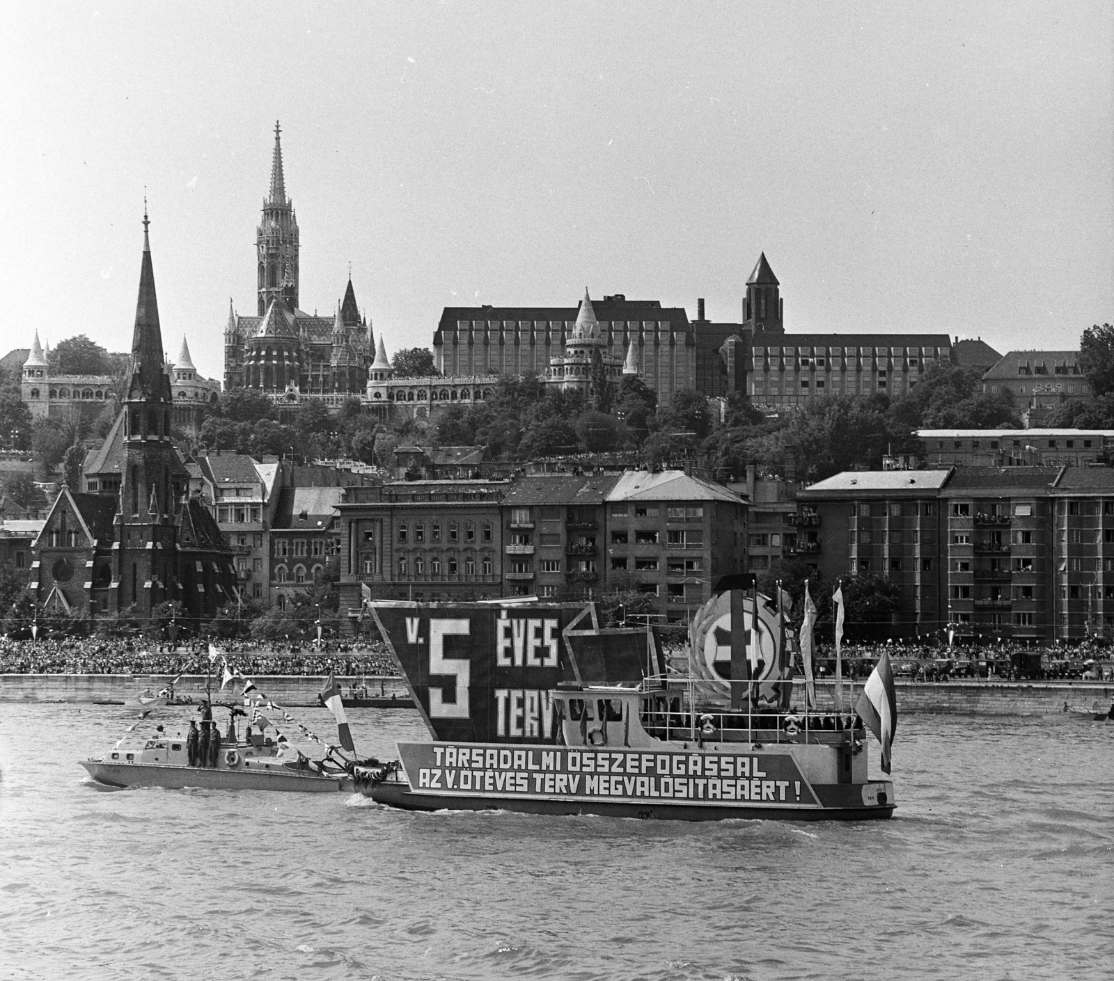 Hungary, Budapest, augusztus 20-i vízi és légiparádé a Dunán, háttérben a Szilágyi Dezső téri templom és a Bem rakpart házai., 1977, MHSZ, ship, church, flag, hotel, warship, political decoration, crest, AN 2 corvette warship, Kitűző V. ship, Fortepan #30798