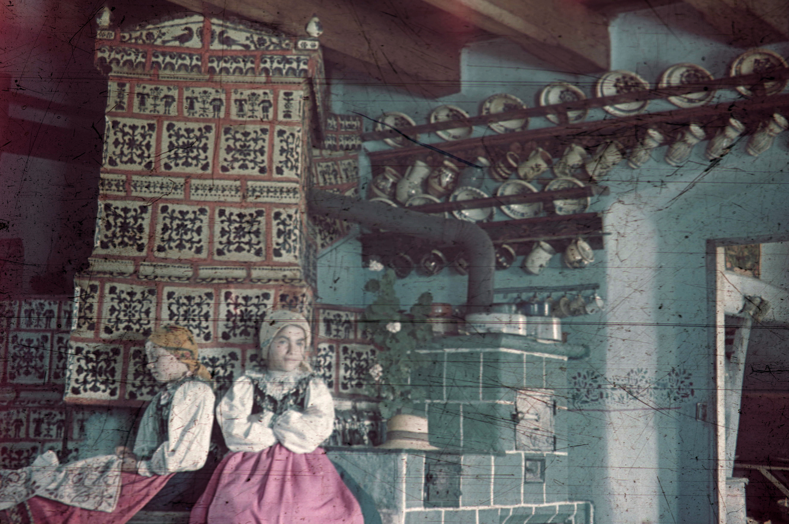 Romania,Transylvania, Beszterce környéki szász ház konyhája, helyi motívumokkal díszített cserépkályha, lányok szász népviseletben., 1940, Fortepan, hat, village, colorful, tile stove, flower, handcraft, folk costume, fireplace, interior, ceramics, girl, double portrait, headscarf, plate, cooking-stove, Fortepan #3094