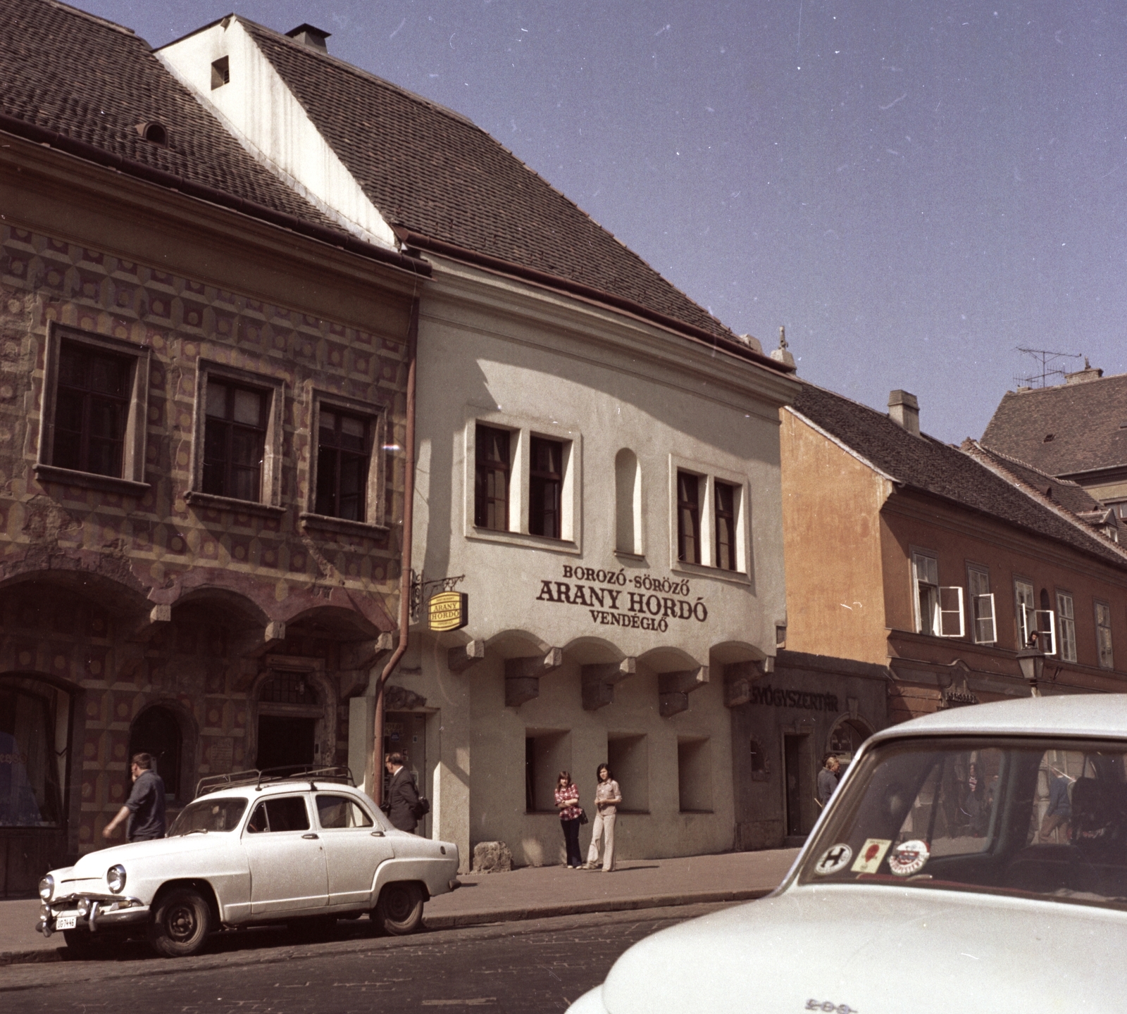 Magyarország, budai Vár, Budapest I., Tárnok utca 16., Anna utca sarok. Az Anna utcát lezáró Gyógyszertár feliratú fal feltehetőleg filmforgatás díszlete., 1975, Építésügyi Dokumentációs és Információs Központ, VÁTI, filmforgatás, színes, vendéglő, francia gyártmány, díszletháttér, automobil, Simca-márka, Simca Aronde, Budapest, országjelzés, Fortepan #31001