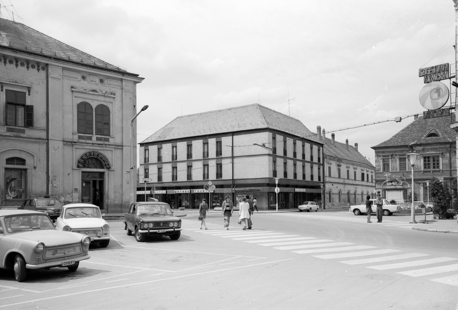 Hungary, Szigetvár, Zrínyi tér, Oroszlán szálló a Széchenyi utca és a Vár utca torkolatánál. Jobbra az oroszlános Zrínyi-emlékmű, Gerendai István alkotása., 1979, Építésügyi Dokumentációs és Információs Központ, VÁTI, Trabant-brand, street view, genre painting, Skoda-brand, neon sign, Polski Fiat-brand, lamp post, number plate, crosswalk, building, automobile, Fortepan #31021