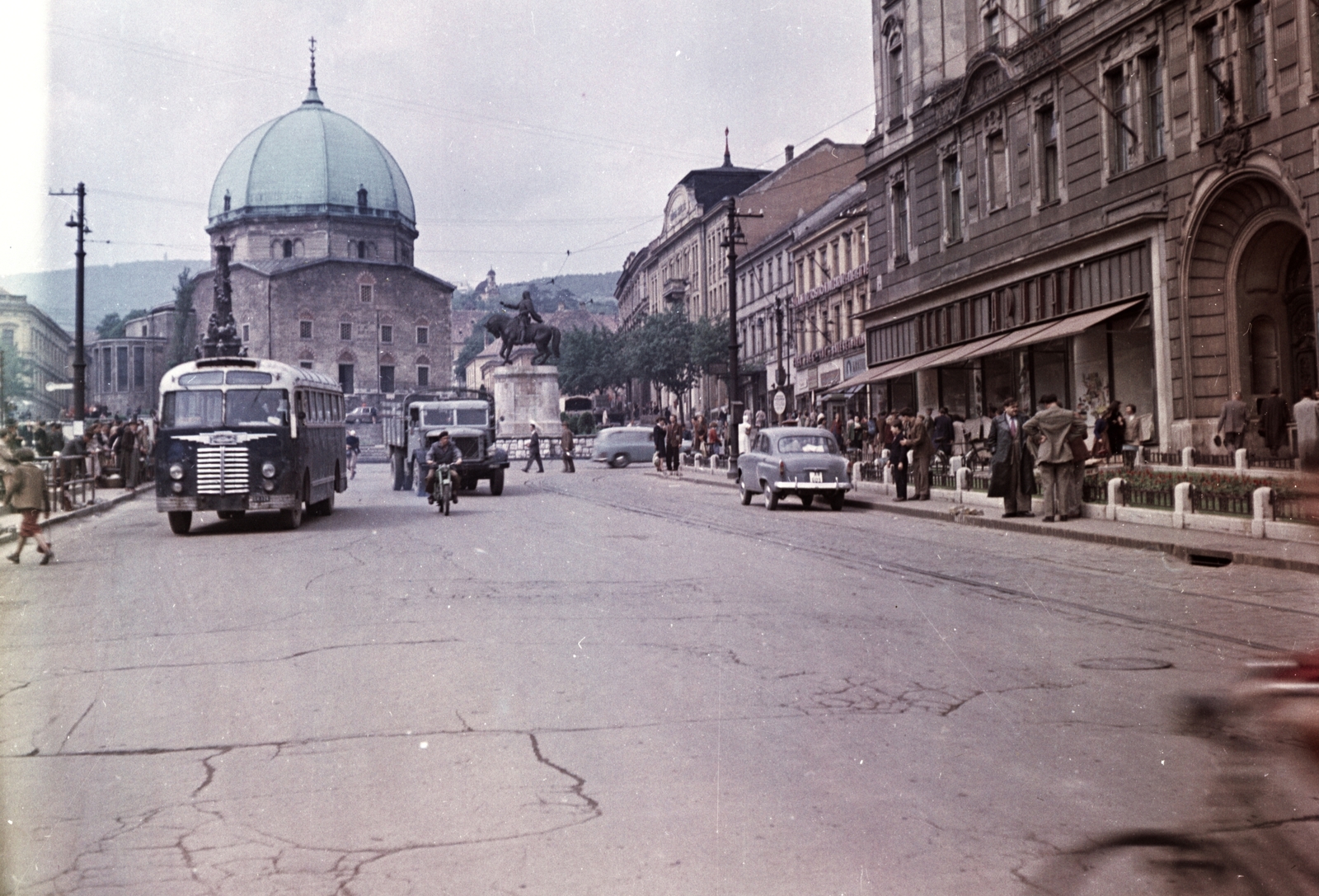 Magyarország, Pécs, Széchenyi tér, távolabb a Dzsámi előtt a Szentháromság-szobor és Hunyadi János szobra, jobbra a Városháza., 1958, Építésügyi Dokumentációs és Információs Központ, VÁTI, közlekedés, jármű, templom, színes, forgalom, autóbusz, szovjet gyártmány, motorkerékpár, magyar gyártmány, szobor, járókelő, teherautó, utcakép, életkép, Ikarus-márka, Moszkvics-márka, Csepel-márka, villamos, buszmegálló, automobil, Ikarus 30, sínpálya, lovas szobor, Moszkvics 402, Csepel B-350/D-350, Hunyadi János-ábrázolás, Fortepan #31210
