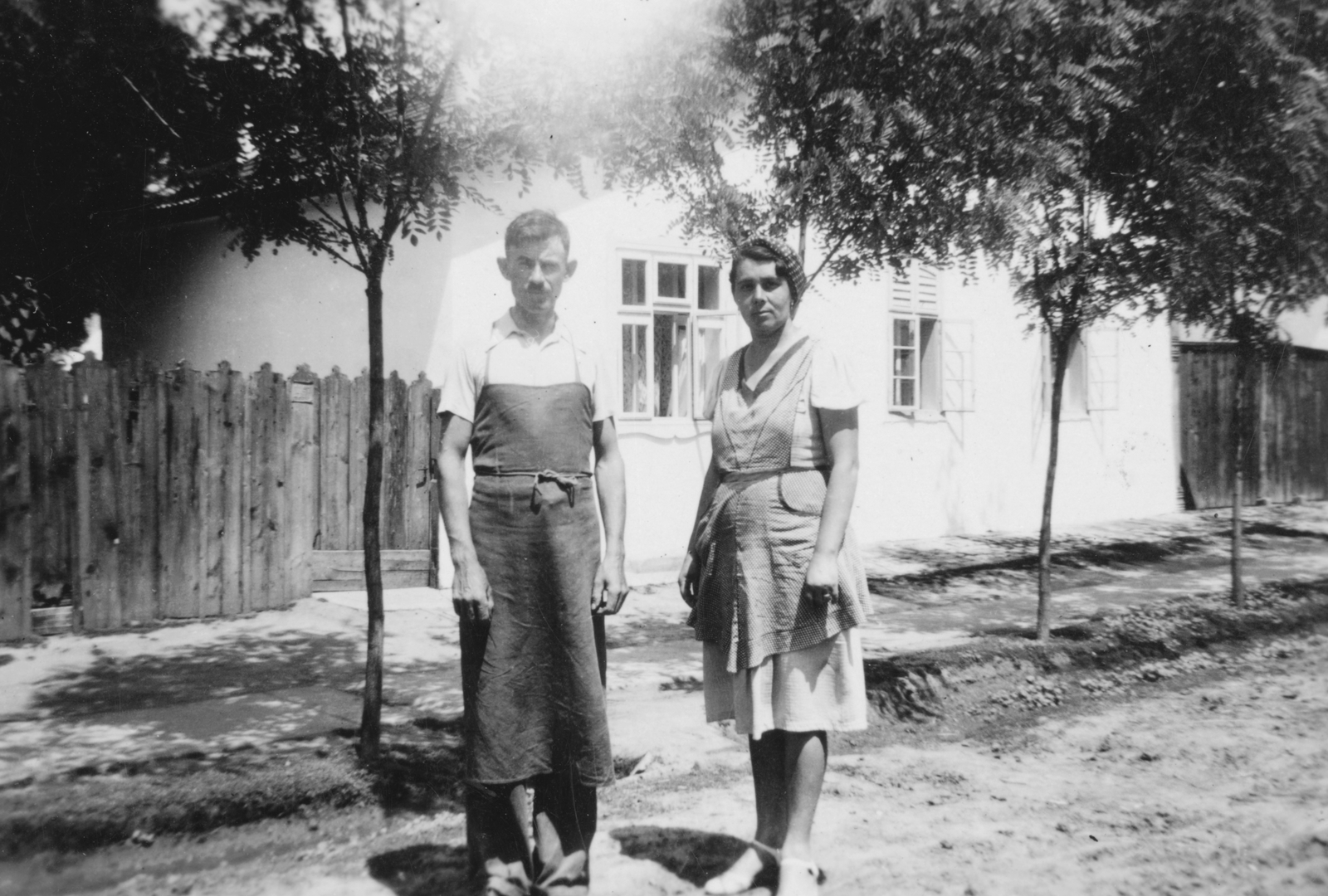 Hungary, Kunmadaras, kerékgyártó mester és felesége., 1938, Anderle Lajosné, street view, lath fence, man, woman, apron, double portrait, Fortepan #31427