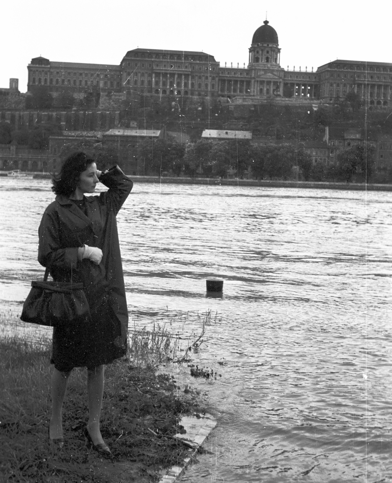 Hungary, Budapest V., pesti alsó rakpart az Eötvös térnél, szemben a Budavári Palota (korábban Királyi Palota)., 1965, Pálinkás Zsolt, portrait, fashion, flood, wharf, nylon fabric jacket, handbag, posture, lady, Danube, Budapest, Fortepan #31505