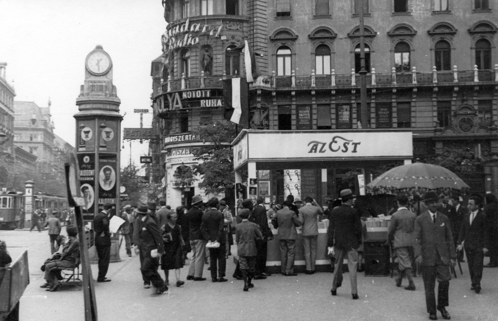 Hungary, Budapest VIII., Blaha Lujza tér, Az Est pavilonja a Nemzeti Színház mellett, József körút - Rákóczi út sarok közelében., 1935, Jurányi Attila, ad, hat, flag, sunshades, watch, pedestrian, street view, genre painting, tram, ad pillar, breech, tram stop, Az Est newspaper, Budapest, book seller, Fortepan #31846