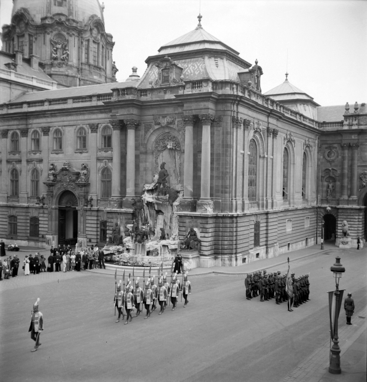 Hungary, Budapest I., a Királyi Palota (később Budavári Palota) Hunyadi udvara, Mátyás király kút. Őrségváltás a főőrségi épület előtt a Szent István-napi ünnepségen. A felvétel a Királyi Istálló épületéből készült, 1938, Pálinkás Zsolt, festive, gas lamp, guard, Budapest, Fortepan #32183