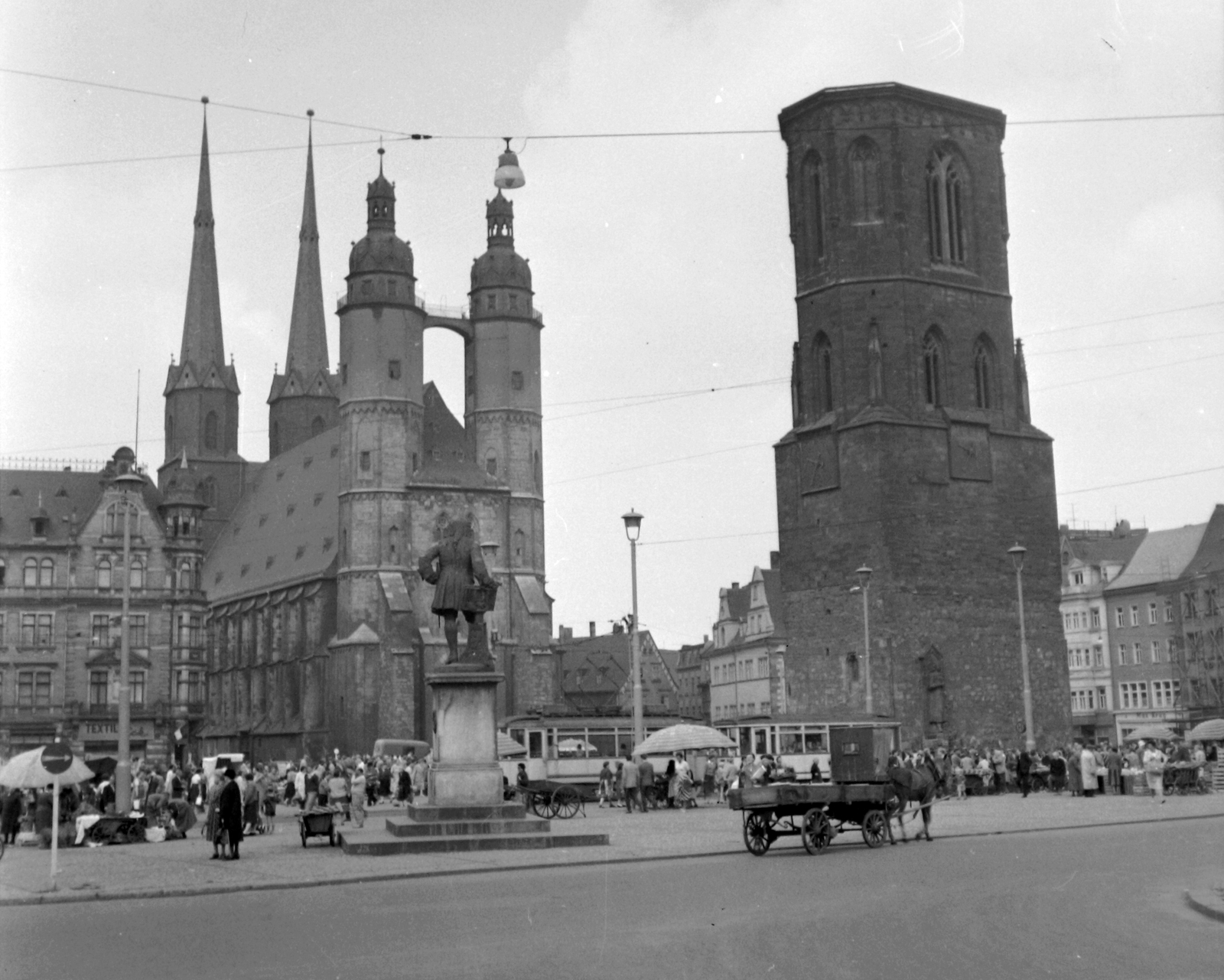 Németország, Halle, Marktplatz, szemben a Szűz Mária-templom (Marktkirche Unser Lieben Frauen, auch Marienkirche), előtte Händel szobra és a Vörös Torony (Roter Turm)., 1960, Gyöngyi, templom, piac, szobor, lovaskocsi, életkép, villamos, NDK, lámpaoszlop, kézikocsi, Fortepan #32666