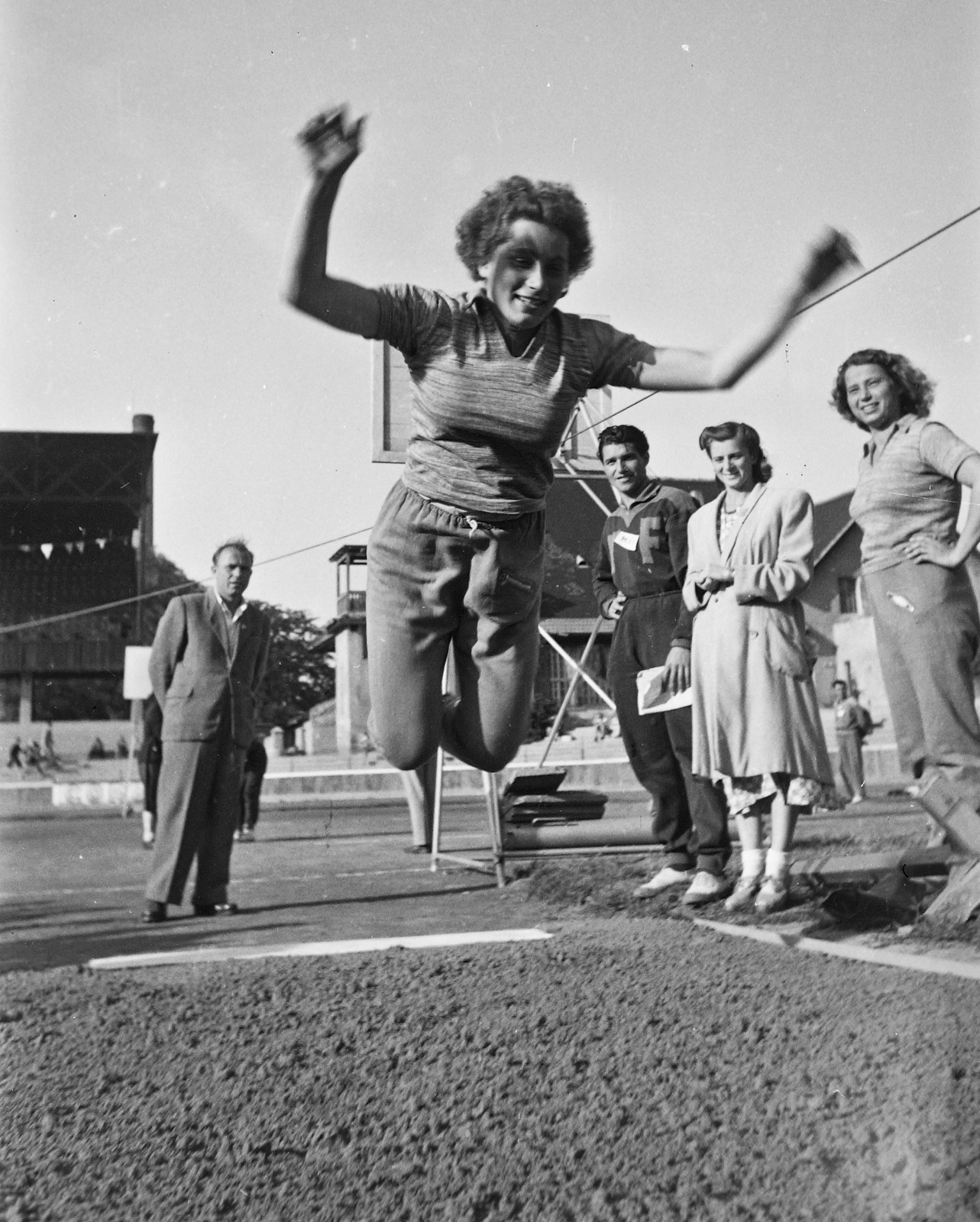 Hungary, Budapest IX., Üllői út, FTC stadion. MHK próba élsportolóknak. Novák Éva ugrik, a homok mellett Novák Ilona nézi, mindketten későbbi olimpiai bajnok úszók., 1949, Kovács Márton Ernő, long jump, MHK movement, Budapest, women, Fortepan #33202