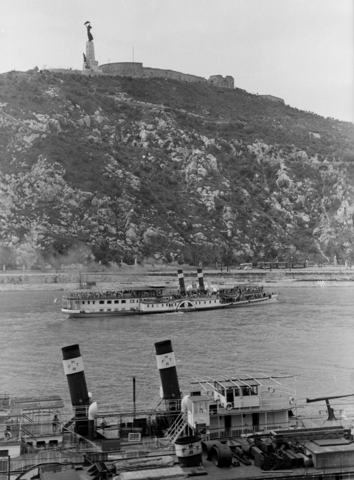 Hungary, Budapest V., Nemzetközi hajóállomás kikötője a Belgrád rakparton. A Duna közepén a Szent István, előtérben a Szent Imre lapátkerekes gőzhajó, háttérben a Gellért-hegy., 1949, Kovács Márton Ernő, ship, steamboat, Szőke Tisza II./Felszabadulás/Szent Imre/Sas/IV. Károly ship, Szent István/Queen Zita ship, Budapest, chimney, Danube, mountain, sculpture, Fortepan #33675