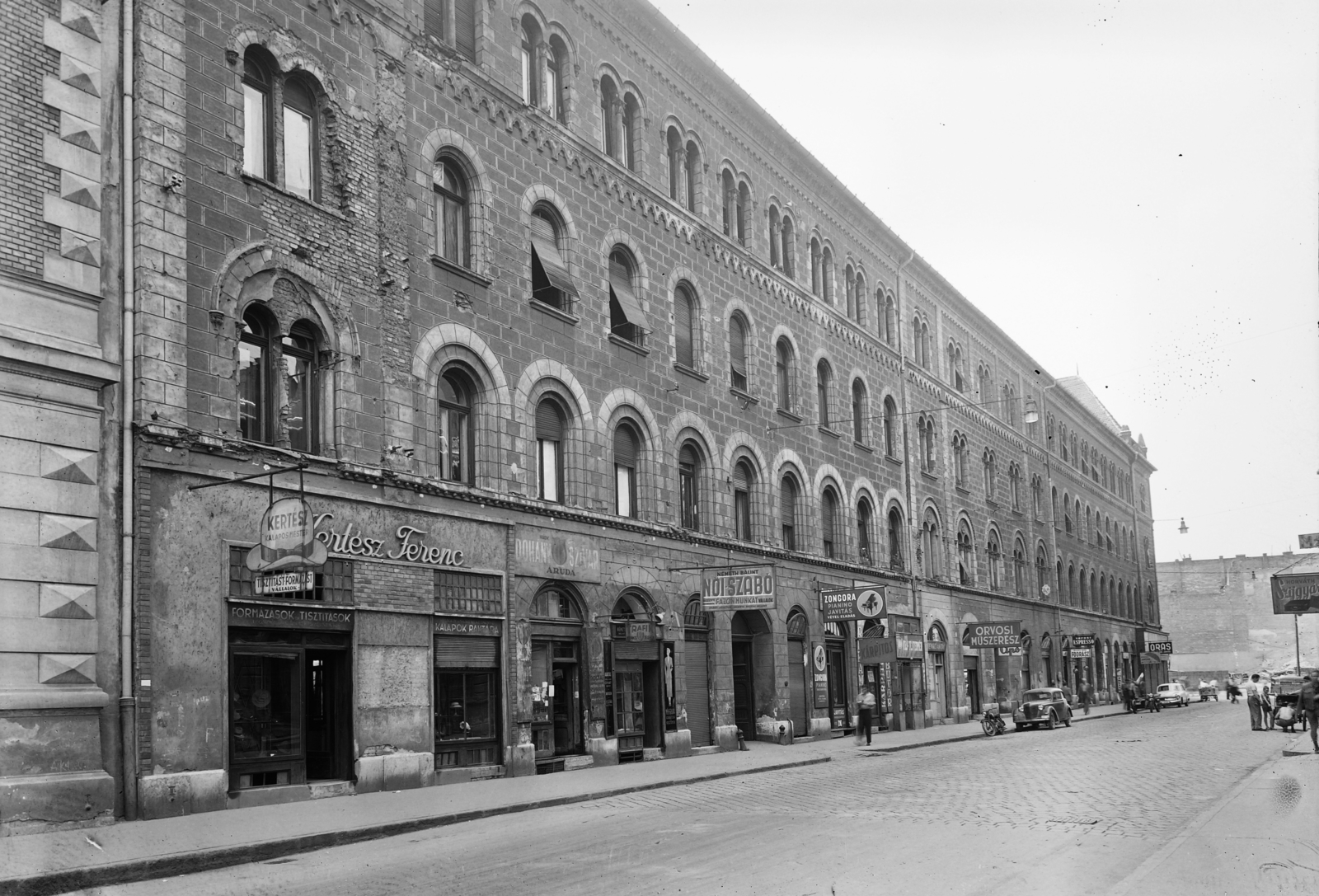 Hungary, Budapest VIII., Luther utca, háttérben a lerombolt Divatcsarnok helye a Rákóczi út - Szövetség utca sarkánál., 1957, UVATERV, sign-board, street view, genre painting, cigar, tobacco shop, hairdresser, automobile, subway construction, umbrella repair, tailors, piano repair specialist, artisan, dairy, clockmaker, saddler, tobacco, Budapest, Fortepan #3762