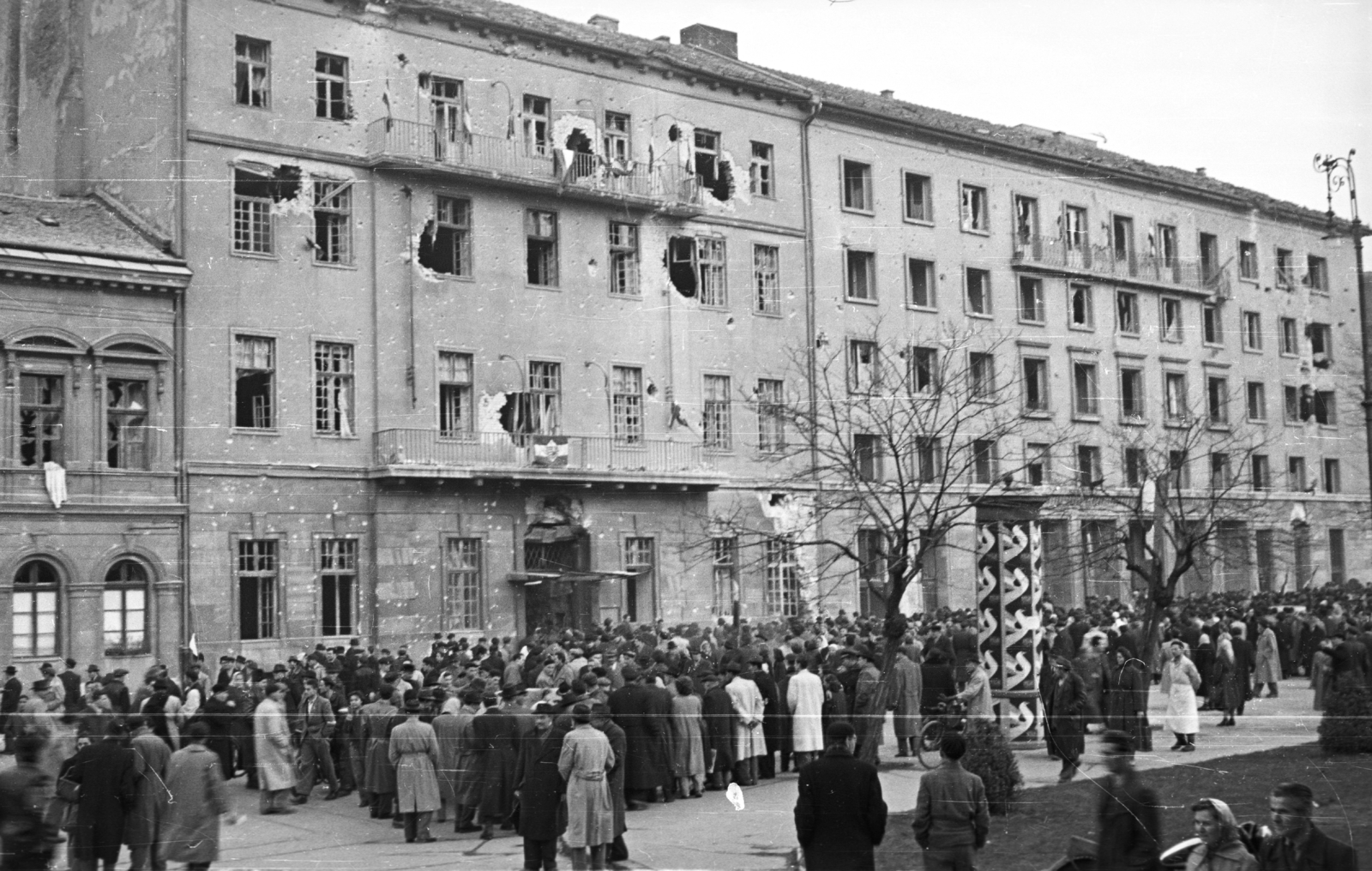 Hungary, Budapest VIII., II. János Pál pápa (Köztársaság) tér, MDP Budapesti Pártbizottságának székháza., 1956, Nagy Gyula, war damage, poster, Party Headquarters, mass, revolution, pedestrian, ad pillar, damaged building, Budapest, Fortepan #39903