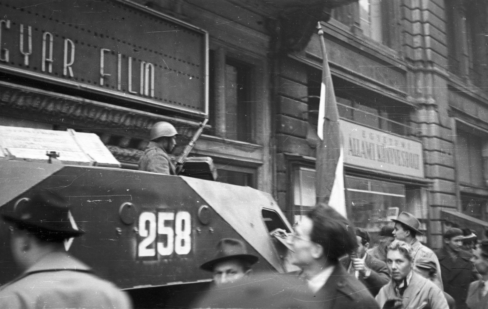 Hungary, Budapest V., Kossuth Lajos utca, Puskin mozi., 1956, Nagy Gyula, flag, Soviet brand, armoured car, revolution, pedestrian, book store, weapon, store display, movie theater, combat vehicle, Budapest, Fortepan #39975