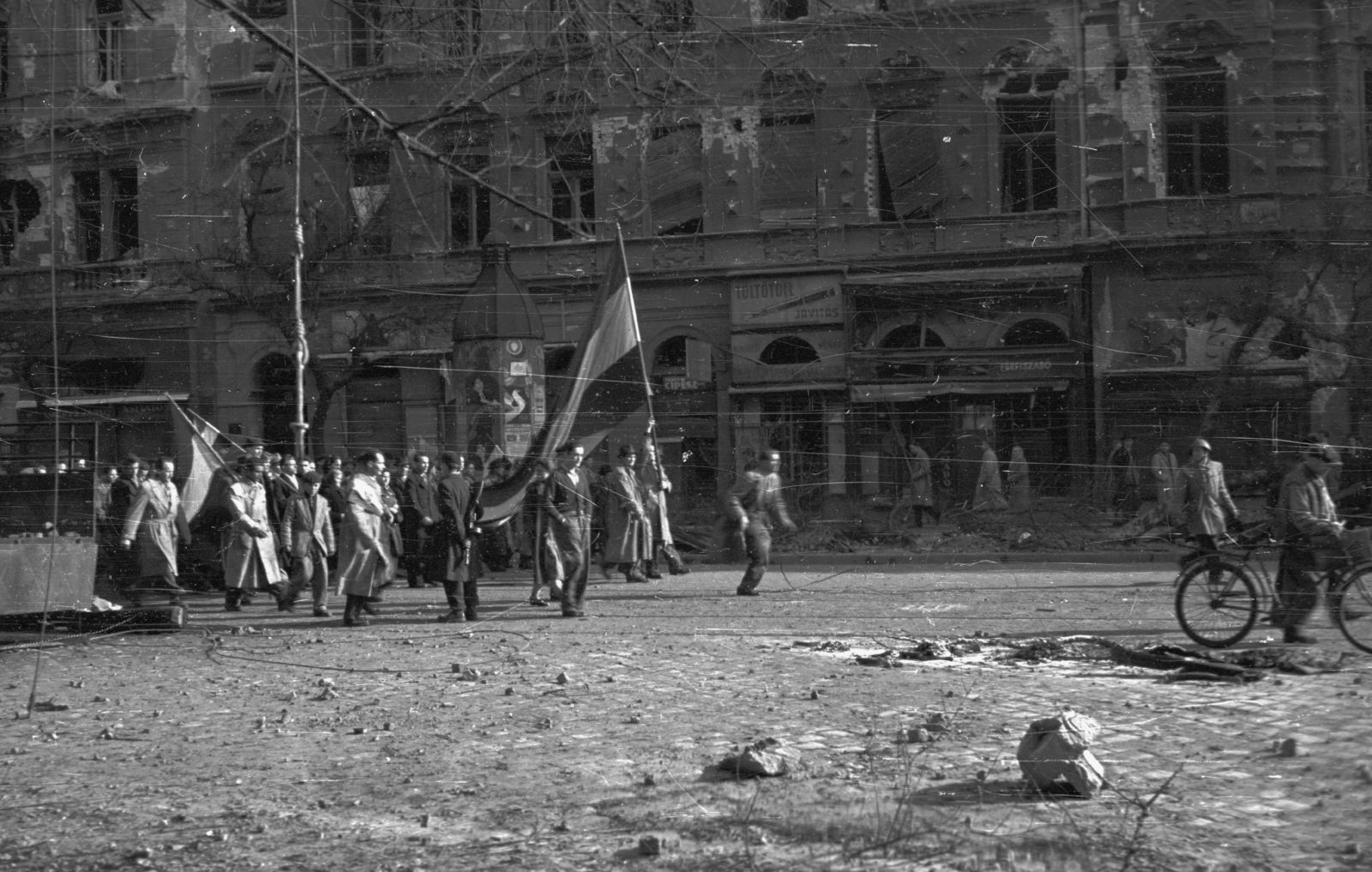 Magyarország, Budapest VIII., József körút 68. a Nap utca sarkán., 1956, Nagy Gyula, háborús kár, zászló, cégtábla, forradalom, utcakép, felvonulás, Budapest, épületkár, Fortepan #40172