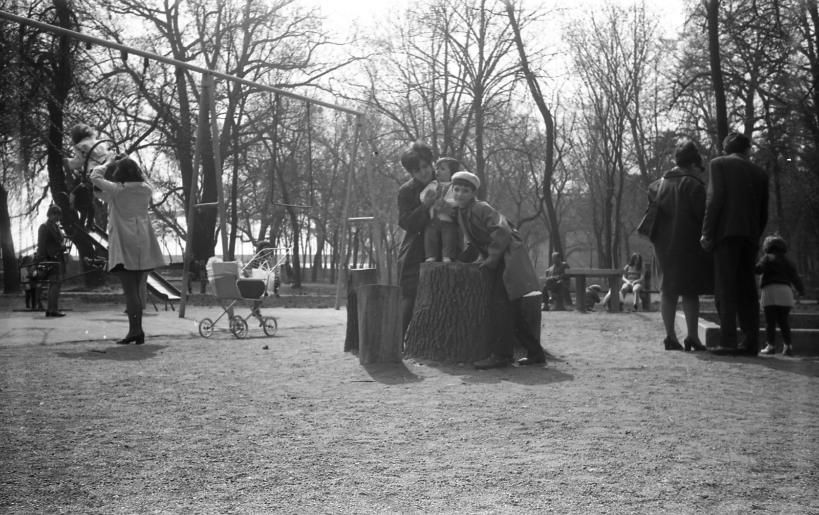 Magyarország, Szeged, Stefánia (Tanácsköztársaság útja), játszótér, háttérben, a fák mögött a Belvárosi híd., 1973, Varga János, fatönk, gyerekek, játszótér, hinta, Fortepan #40325