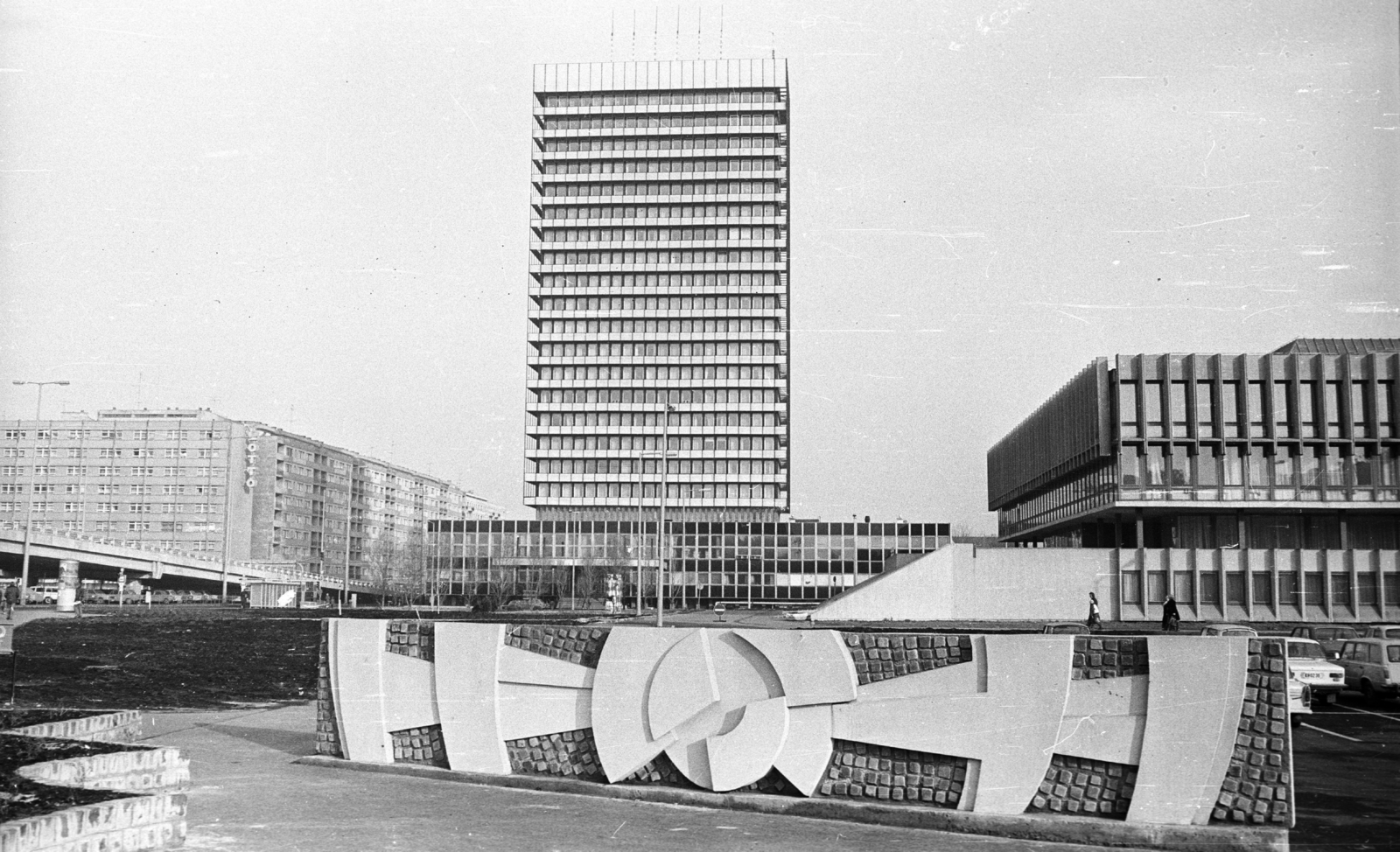 Hungary, Budapest XIII., Róbert Károly körút - Váci út - Teve utca által határolt terület. Gyurcsek Ferenc Domborműves térplasztikája mögött a SZOT irodaház (később Nyugdíjfolyósító), jobbra a kerületi pártház (később Magyar Államkincstár Budapesti és Pest Megyei Igazgatóság) épülete., 1984, Angyalföldi Helytörténeti Gyűjtemény, relief, high-rise building, tall house, overpass, Budapest, Fortepan #41200