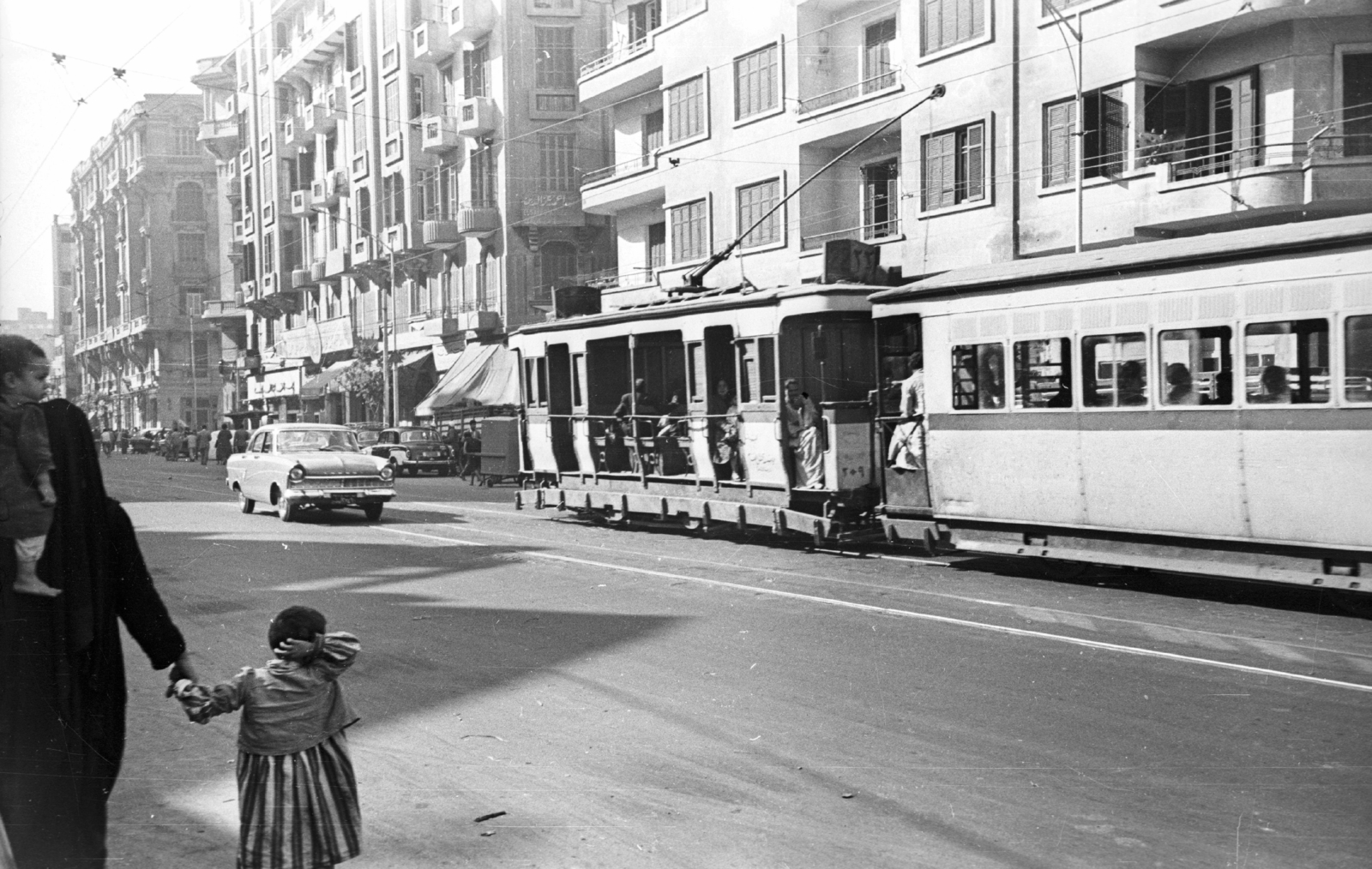 Egypt, Cairo, El-Geish út az Attaba tér felé nézve., 1961, MZSL/Ofner Károly, street view, genre painting, tram, automobile, Arabic script, sitting on the shoulders, hold hands, public transport line number, Fortepan #41828