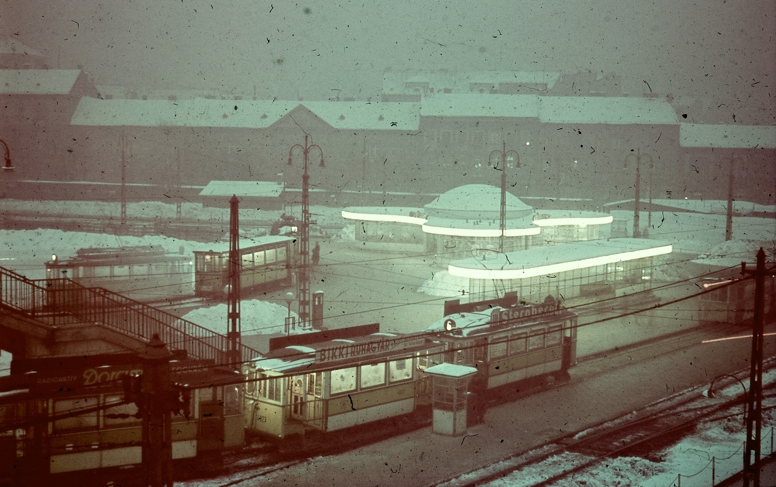 Magyarország, Budapest I.,Budapest II., Széll Kálmán tér a gombával., 1943, Konok Tamás id, reklám, tél, színes, forgalom, utcakép, villamos, lámpaoszlop, villamosmegálló, Budapest, Bikki Ruhagyár, viszonylatszám, BVVV M-típus, Fortepan #42501