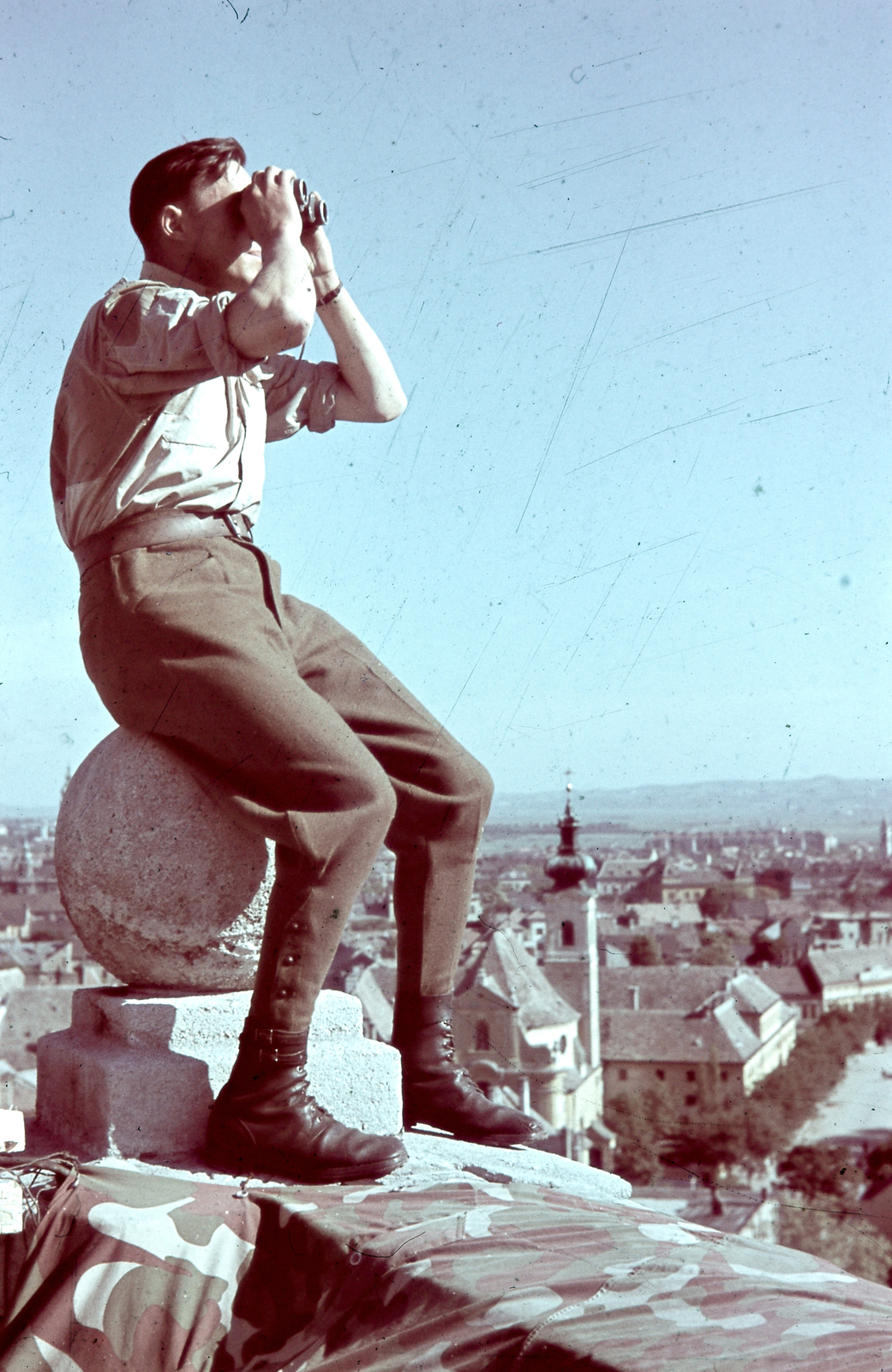 Magyarország, Győr, légi megfigyelő a Püspökvár tornyán, háttérben a Bécsi kapu (Erzsébet) téren a karmelita templom., 1944, Konok Tamás id, színes, bombázás, második világháború, barokk-stílus, sátorlap, Kármeliták, katona, messzelátó, távolba tekint, távcső, Fortepan #42555