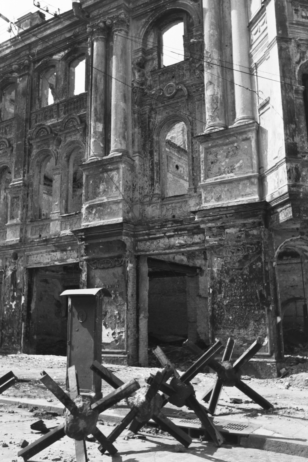 Ukraine, Kyiv, Architektora Horodeckoho (Karl Marksa, eredetileg Nyikolajevszkaja) utca, az Egyesült Déloroszországi Ipari Bank palotájának romjai., 1942, Konok Tamás id, war damage, damaged building, road block, anti-tank obstacles, Fortepan #43111