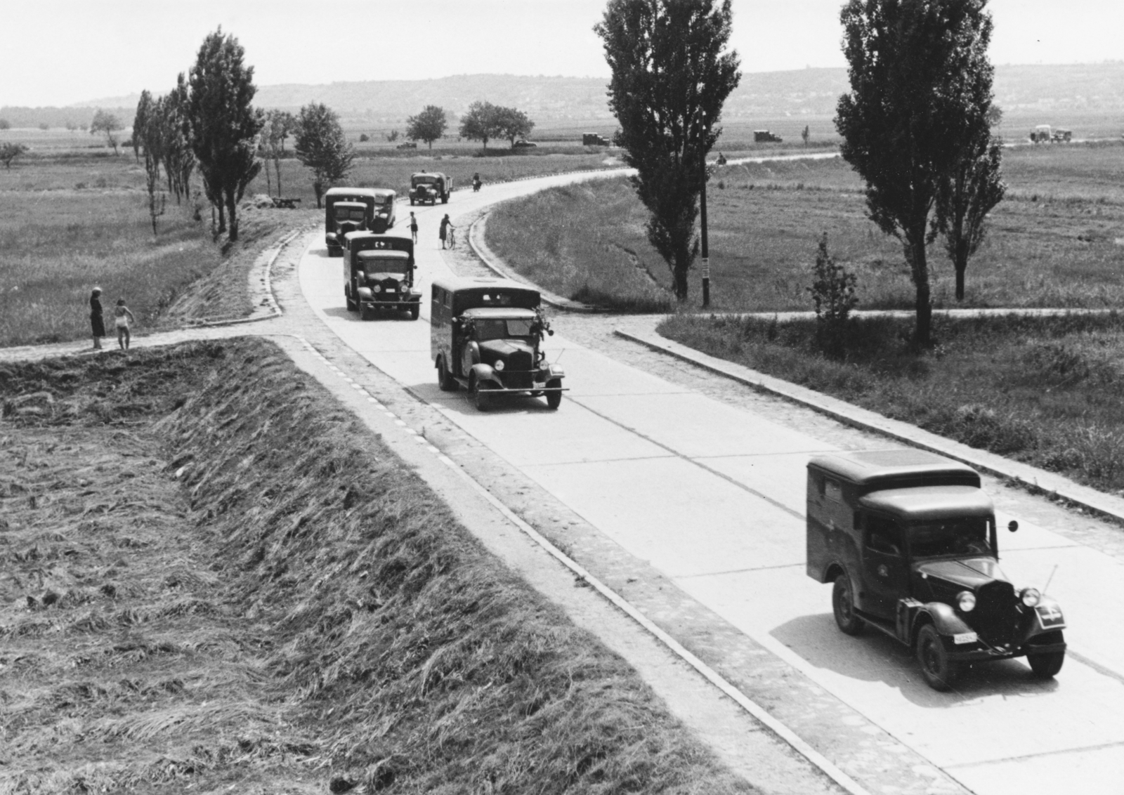 Hungary, Érd, a Balatoni út az Érd alsó-Tétényliget közötti vasúti töltésről nézve, háttérben keresztben a 6-os főút. A Magyar Királyi Haditudósító század gépkocsi menetoszlopa,, 1942, Konok Tamás id, railway, commercial vehicle, military, landscape, Fortepan #43786