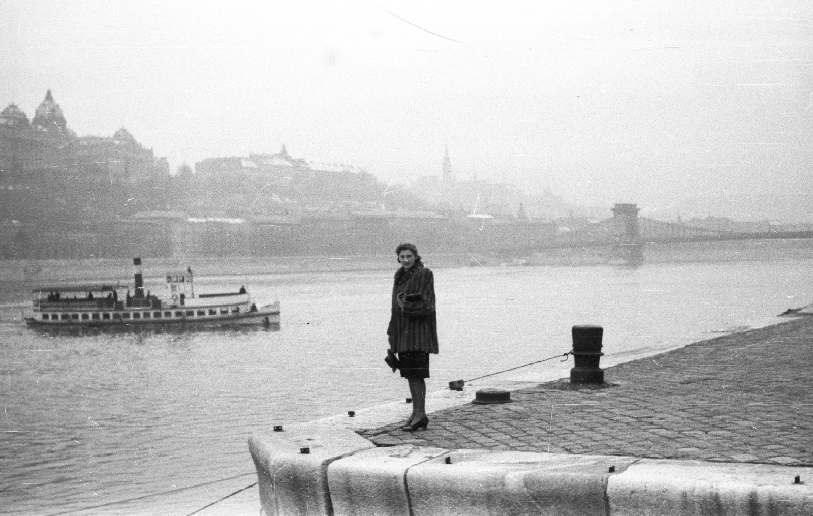 Magyarország, Budapest V., pesti alsó rakpart a Vigadó térnél, háttérben a Széchenyi Lánchíd és a budai Vár., 1941, Ludovika, divat, hajó, bunda, vízpart, rakpart, retikül, gőzhajó, hölgy, Budapest, függőhíd, William Tierney Clark-terv, kikötőbak, Fortepan #43960