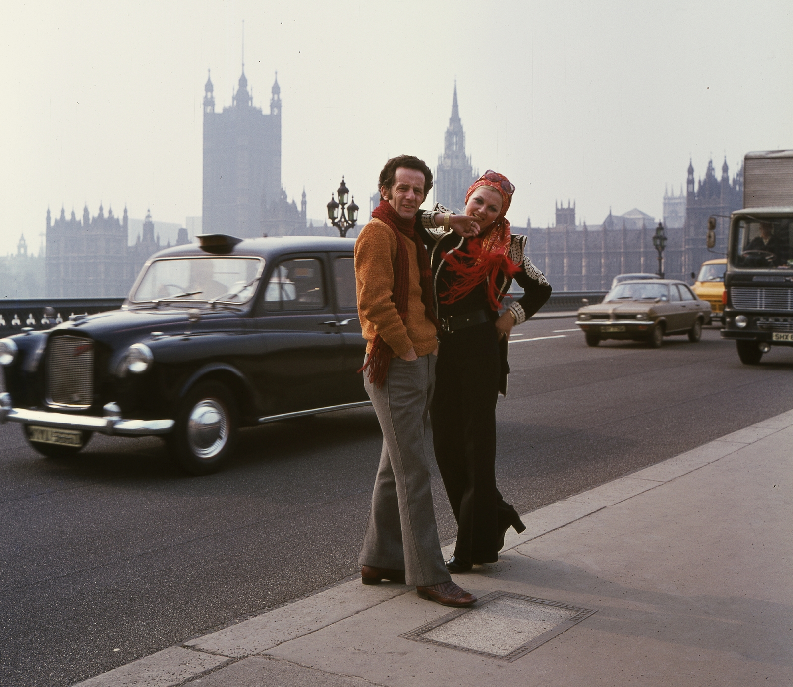 United Kingdom, London, Westminster híd, háttérben a Parlament. Schiffer Pál filmrendező és Bodó Sztenya manöken., 1973, Schiffer Pál, fashion, colorful, taxicab, double portrait, parliament, Neo-Gothic-style, automobile, Charles Barry-design, fashion photography, Fortepan #44667