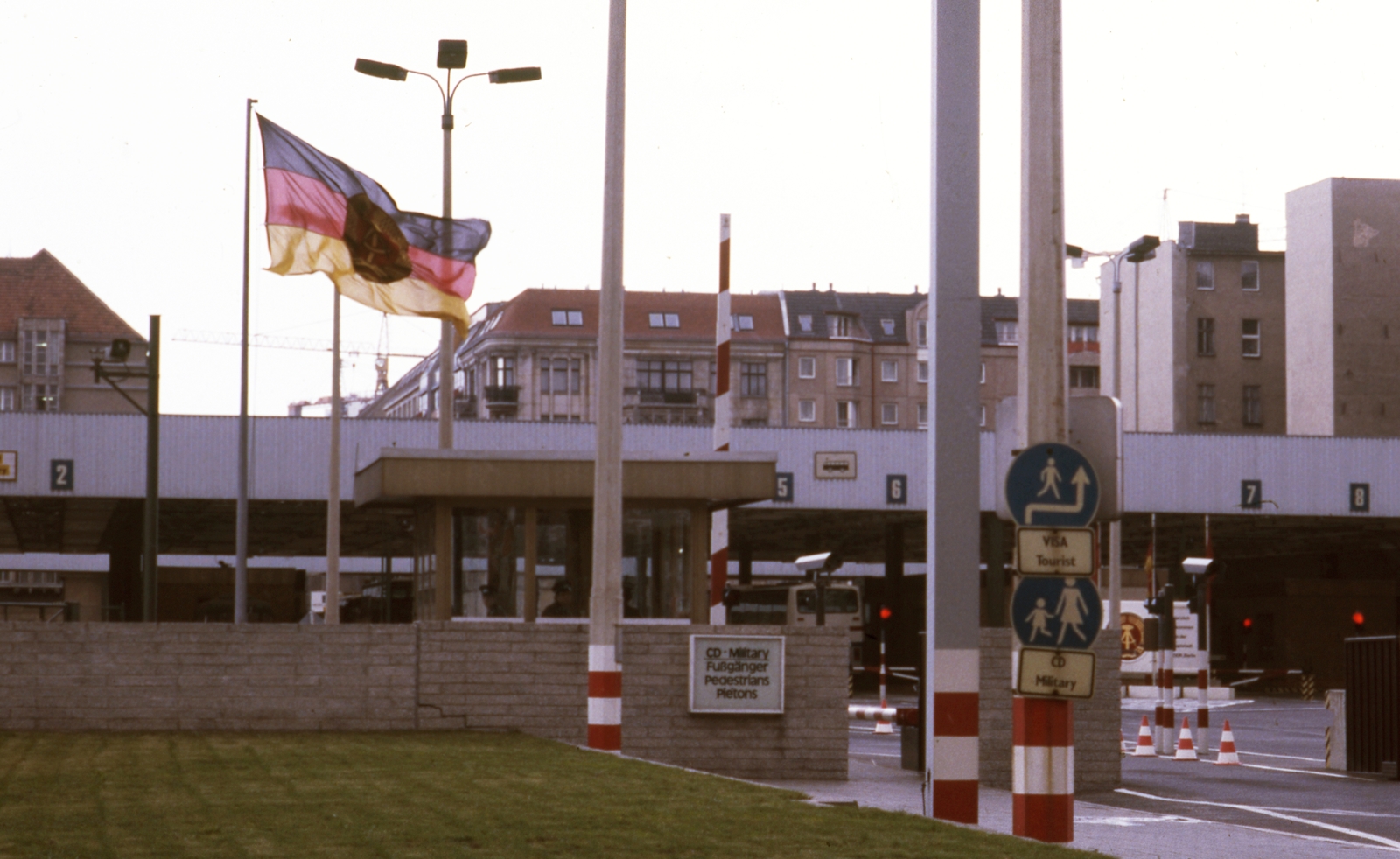 Germany, Berlin, Friedrichstrasse. Határátkelőhely Nyugat-Berlin és Kelet-Berlin között a nyugati oldalról, a Zimmerstrasse felől nézve., 1988, Urbán Tamás, colorful, flag, GDR, border crossing, East-Berlin, West Berlin, multilingual sign, Fortepan #44764