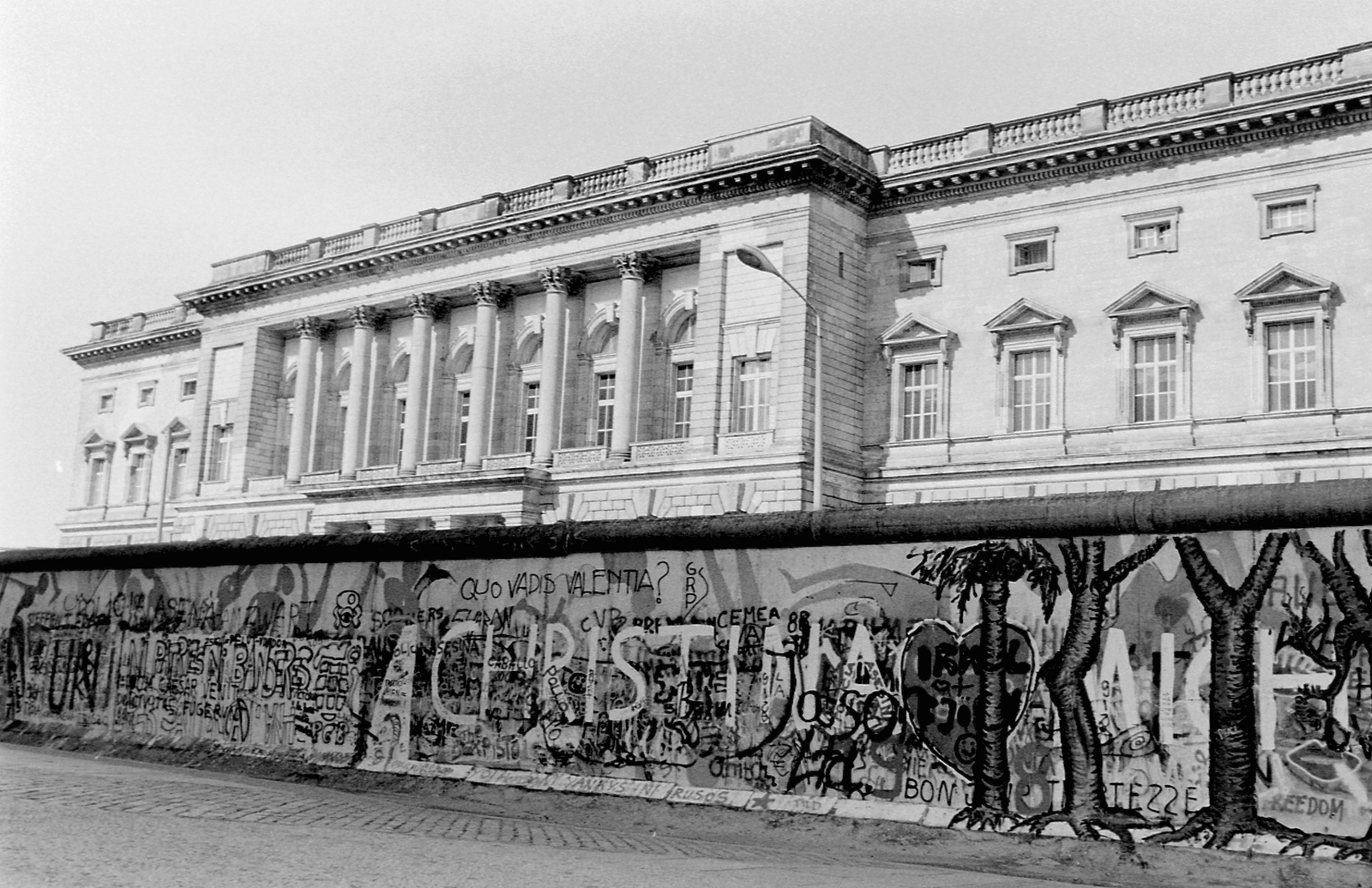 Németország, Berlin, Niederkirchnerstrasse, a berlini fal nyugat felől. A kelet-berlini oldalon álló épületben működött az Állami Tervbizottság (egykor Porosz tartományi parlament, ma Fővárosi képviselőház)., 1988, Urbán Tamás, NDK, graffiti, Berlini fal, Kelet-Berlin, Nyugat-Berlin, Fortepan #45337