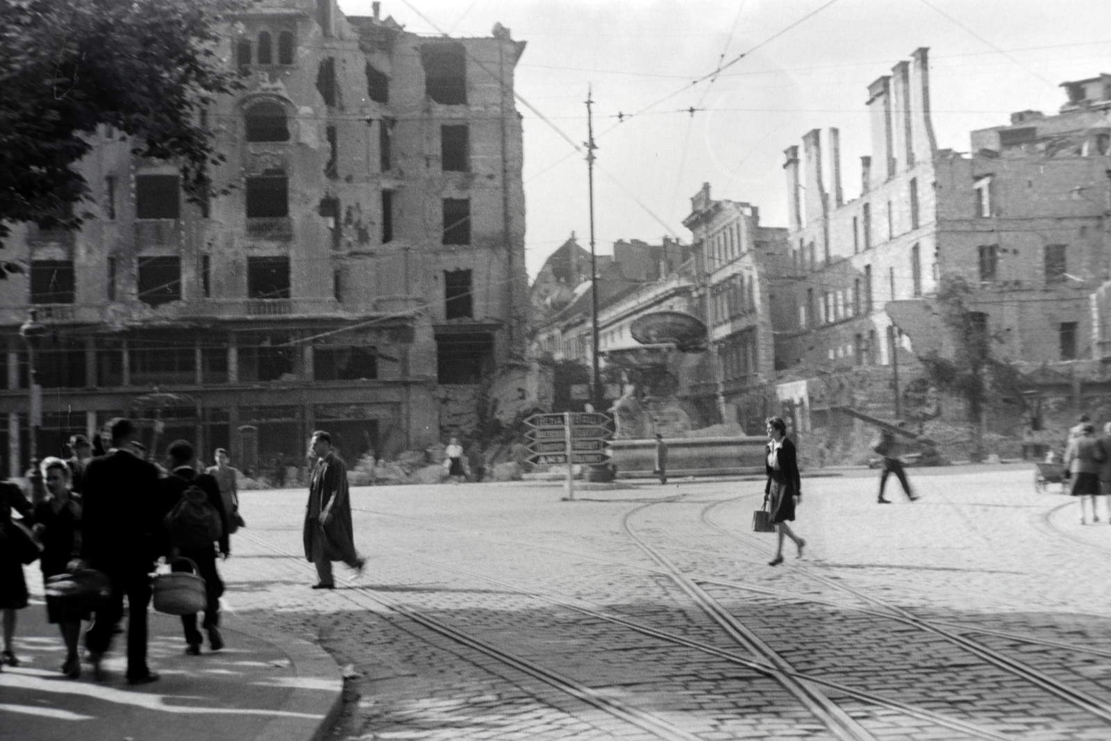 Magyarország, Budapest V.,Budapest IX., Kálvin tér az Üllői út torkolatától a Kecskeméti utca felé nézve., 1945, Fortepan, szökőkút, épületkár, Budapest, útjelző tábla, sínpálya, járókelő, kosár, felsővezeték, Fortepan #45557